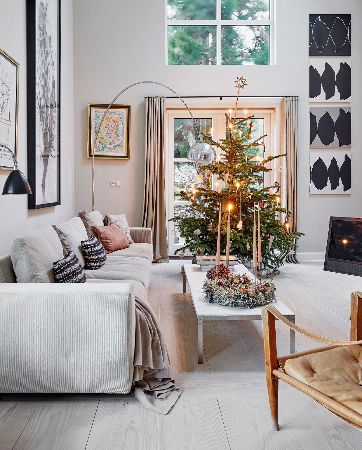 Bank Baseline van Eilersen, kussens Tapet-Cafe. Marmeren koffietafel Poul Kjærholm, kerstkrans met kaarsen gemaakt door Malou Karberg en Henrietta. Inkttekening boven bank Cathrine Raben Davidsen, kunstwerk links naast raam Egill Jacobsen. Lamp Arco van Achille &amp; Castiglioni voor Flos. Vintage leren Safari Chair van Kaare Klint. Vier grafische kunstwerken Ulla Pedersen.