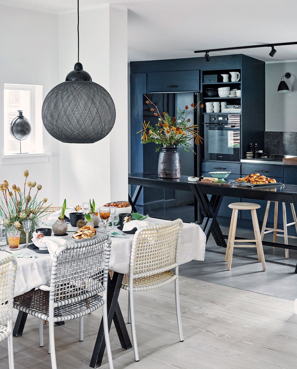 Oude Boform keuken en Ilva tafels geschilderd in Railings van Farrow &amp; Ball. Handvaten kastjes Brandt Collective, tegels Made a Mano. Houten krukken Louisiana Design Butik. Zwarte vaaspot The Travelling Band. Eettafel zelfgemaakt door Henrietta. Stoelen Allu van Paola Navone voor Gervasoni. Hanglamp Non Random Light van Moooi. Tafelkleed en servetten Georg Jensen Damask. Zwart servies Royal Copenhagen. Overig herkomst onbekend.