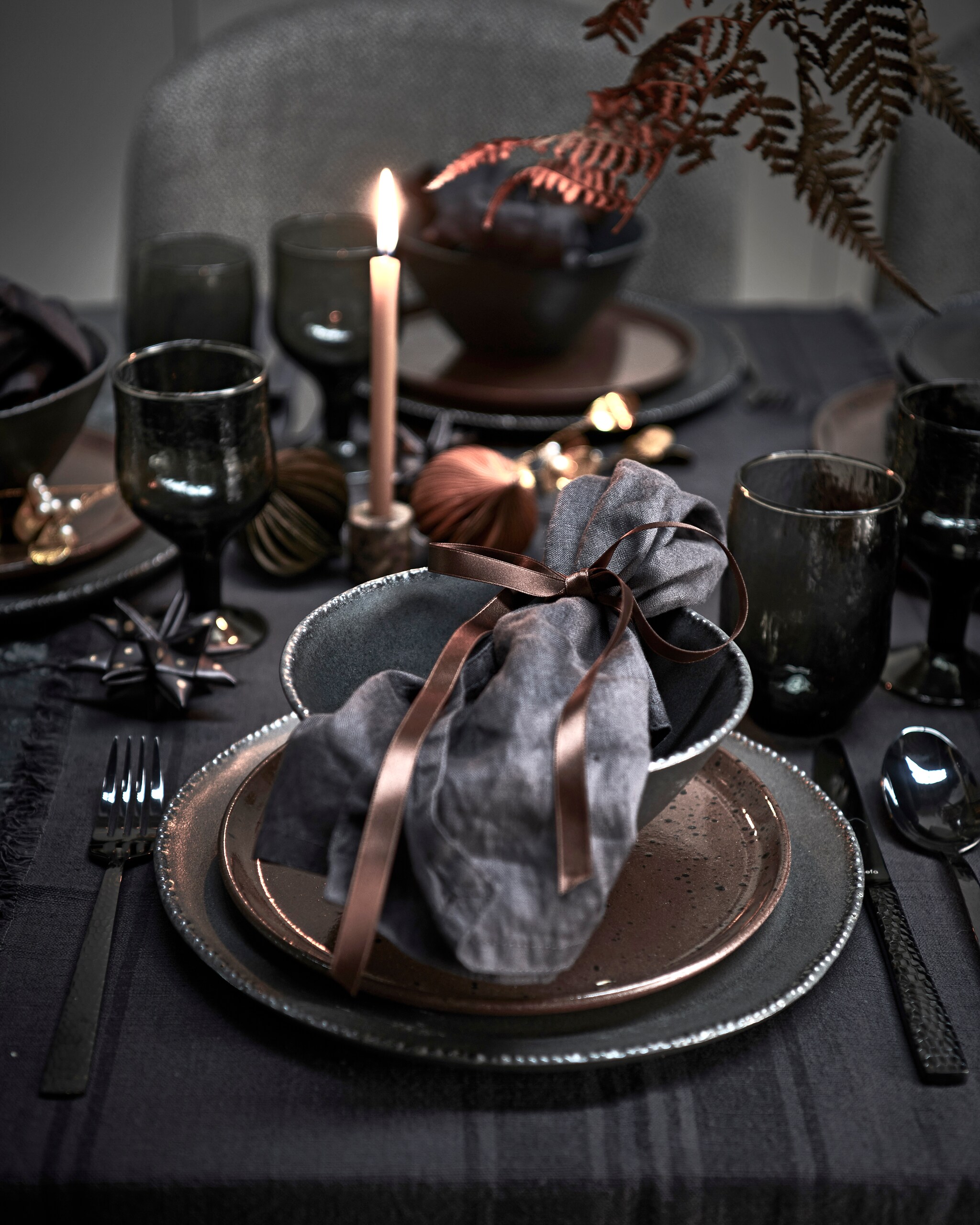 Bloemen, prijs op aanvraag (tuinvanjudith.wordpress.com). Tafelloper € 9,99, zwarte borden, per stuk € 12,99, zwarte kommen, per stuk € 9,99, servetten, set van twee € 9,99 (h&amp;m). Grijze water- en wijnglazen, per stuk vanaf (anna-nina.nl). Bestek van Amefa, 24-delige set € 55,65, grijs gestoffeerde stoelen van Dutchbone, per stuk € 232,35 (vtwonen). Gespikkeld bruin bord, marmeren kandelaar € xxx, lange dunne kaars, kerstbal ster (letoile.store). Metalen mistletoe, set van 2 € 17,50, papieren kerstballen, per stuk € 3,- (bungalow).