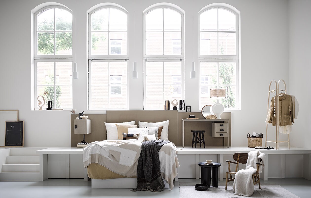Bureau kringloop € 20,- (kringloopwinkelleiderdorp). Ingelijste print op grond groot € 399,- en klein € 299,-, beige-wit plaid € 659,- kaars op vensterbank, set van 3 € 45,- (sukha). Beige ornament op vensterbank € 86,- (vtwonen). Zwarte vaas met handvat € 89,- en gestreepte vaas op vensterbank € 89,-, vloerkleed € 1695,- (couleurlocale). Marmeren schaal op vensterbank € 45,99, beige kussen set van 2 € 45,99, wit kussen € 45,99, dekbedovertrek 200×220 cm € 79,99, zwarte kandelaar naast bed € 15,99, ronde spiegel € 69,99, katoenen toilettas € 19,99, instappers € 25,99, zwarte slippers € 19,99, linnen bloes € 45,99 en witte bloes € 45,99 (zarahome). Witte lampenvoet € 2154,-, zwarte kruk met twee poten en zwarte schaal prijs op aanvraag (covanderhorst). Siervorm rechts op vensterbank € 24,99, zwarte kruk € 59,99, webbing lampenkap € 39,99 en mand € 39,99 (h&amp;m). Minivaas € 15,- en zwarte kan op nachtkastje € 55,- (fermliving). Papieren ornament in zwamvorm op nachtkastje prijs op aanvraag (elsavisser). Gestreept kussen € 110,-, grijs plaid € 255,-, beige mokje € 9,90, kledingrek € 569,- met slinger eraan € 32,90 (letoile.store). Kussen met motief op bed gemaakt van stof Escale Élitis per meter € 225,- (loggerewilpower). Houten fauteuil € 2804,- (homestede). Wit plaid € 199,- (bymolle).