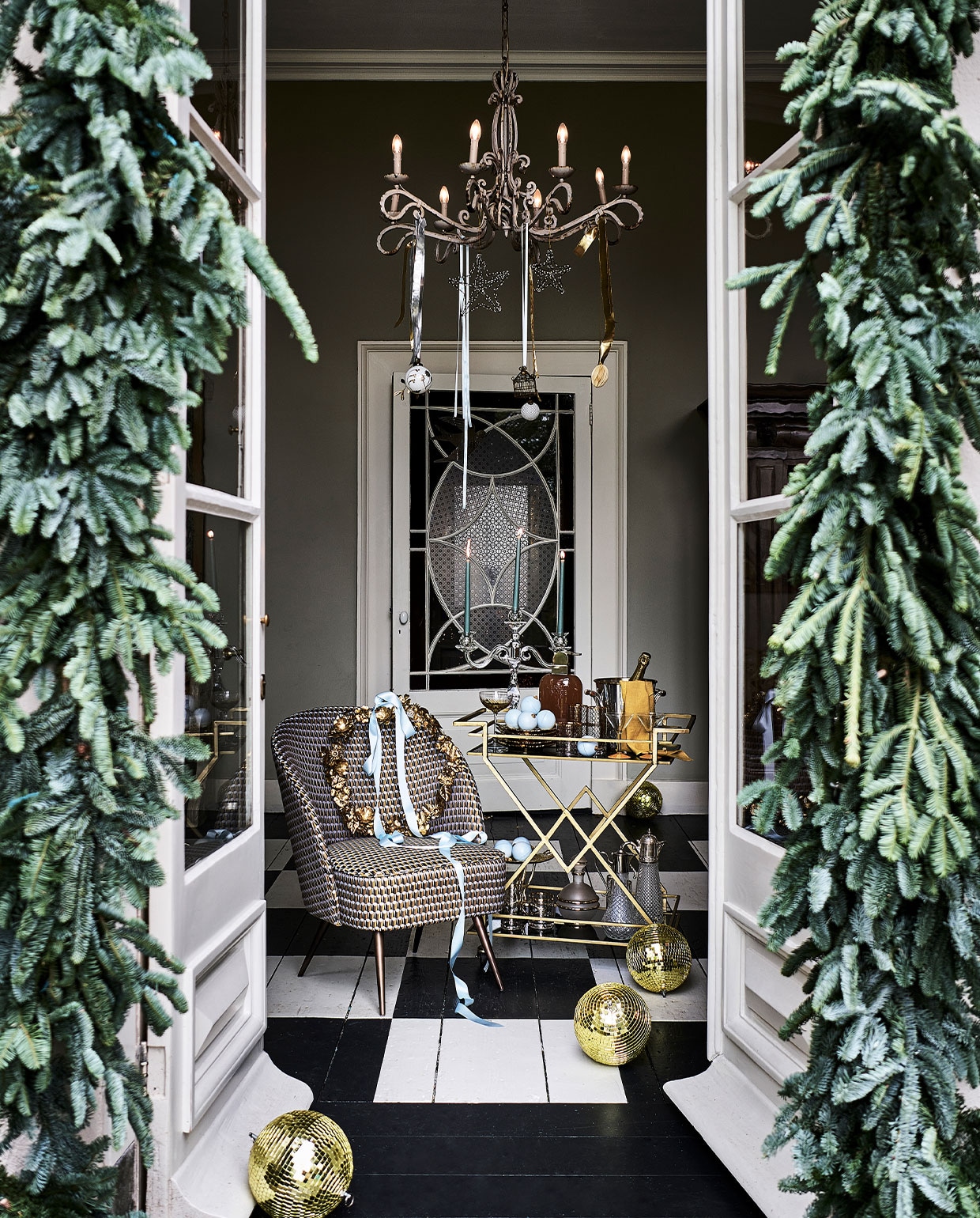Trolley € 599,-, glazen met goudkleurig dessin vanaf € 12,95, cocktailglas links € 12,95, glazen kandelaar € 238,- (nordal). Bloemstyling, p.o.a. (judithslagter). Goudkleurige discoballen, per stuk € 32,50 (spektakelwonen). Blauwe chocolade kerstballen, per stuk € 7,95 (toutpatisserie). Fauteuil € 725,-, borden in bladvorm, per stuk € 32,- (allestedlund). Servet, set van 2€ 12,-, papieren ei in kroonluchter, maat XL € 12,-, krans € 47,- (bungalow). Wijnkoeler € 280,- (wildschut-antiques). Cocktailglazen met gele voet, per stuk € 10,-, drankfles € 95,-, kannen rechtsonder op trolley, per stuk € 65,-, drankfles mat glas met goudkleurige rand € 35,- (harlequin-lisse). Blauwe kaarsen, set van 2€ 1,99 (h&amp;m). Plateau € 159,- (luxurybynature). Handgemaakte en gerecyclede kerstballen in kroonluchter en op trolley, vanaf € 6,95 (weldaad.com). Lint privébezit. Droogbloemen en kersttakken (waterdrinker).