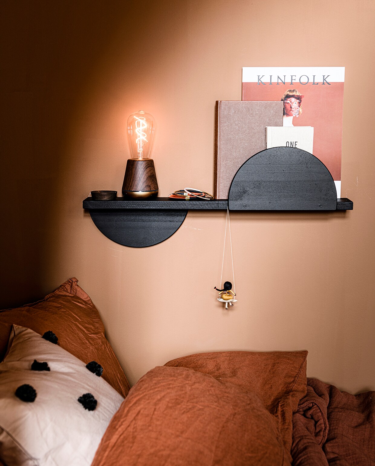 Kussen Dot Tufted van Ferm Living in kleur Sand/Black (vtwonen). Dekbedovertrek en kussensloop in kleur Brick, deken Cinnamon, 100×140 cm van Garbo &amp; Friends (archive-store). Oplaadbare tafellamp Walnut in kleur Satin Brass (humblelights.com). Armbanden (zenza). Memory book One Line a Day (hm.com). Meisje op schommel (dorimu.com). Overig privébezit.