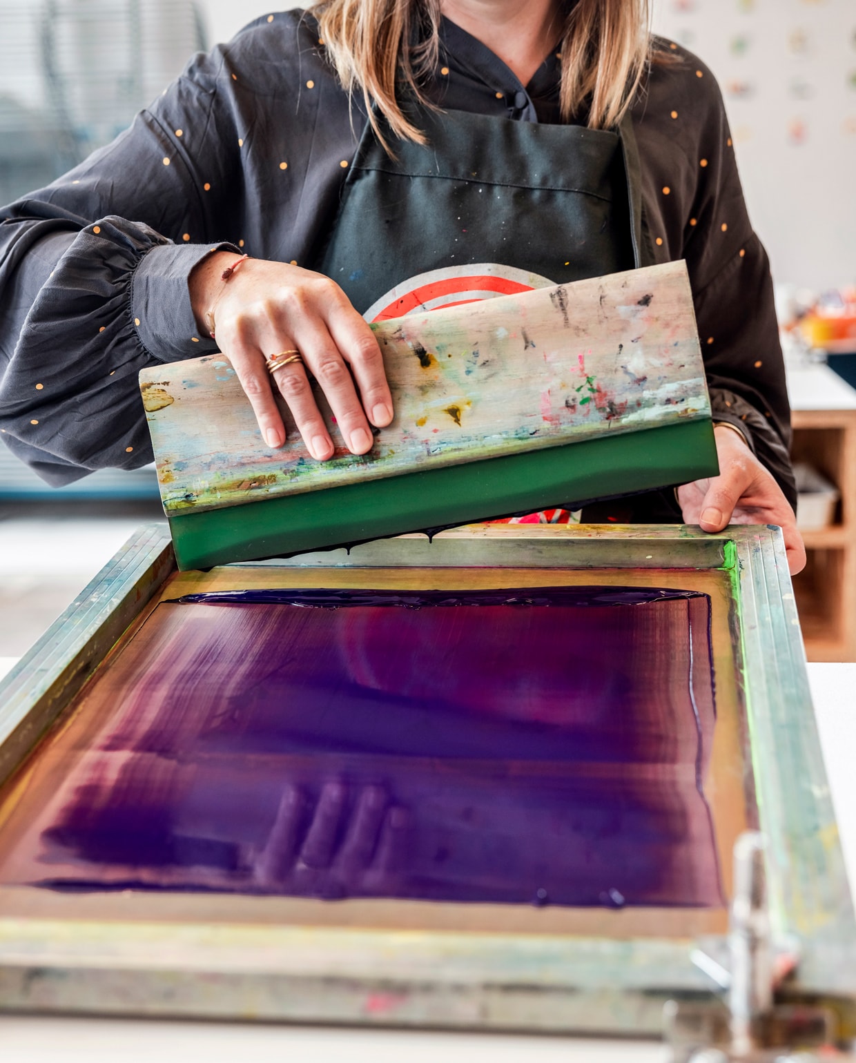 ‘Met de rakel vul ik de gaatjes van het zeef­drukraam met inkt. Zeefdrukken vergt tijd en is arbeidsintensief. Voor elke kleur inkt herhaal je dat proces en per kleur maak je een andere film. Zo bouw je een zeefdruk op uit meerdere lagen.’