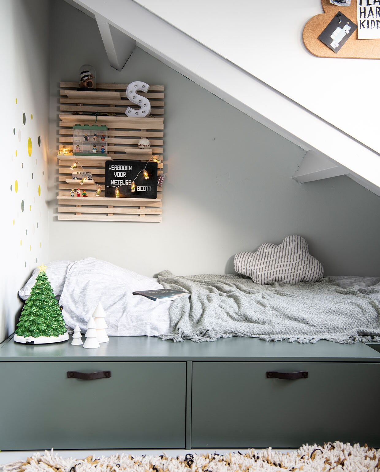 Stage Bed van vtwonen.nl. Dekbedovertrek Witlof for kids. Sprei, witte kerstboom Jysk. Wolk-kussen Made. Wandbord Søstrene Grene. Muurstickers Hema. Groene kerstboom Tuincentrum Osdorp. Kleed Living Maroc. Muurverf Quiet Clearing van Histor. Overig herkomst onbekend.