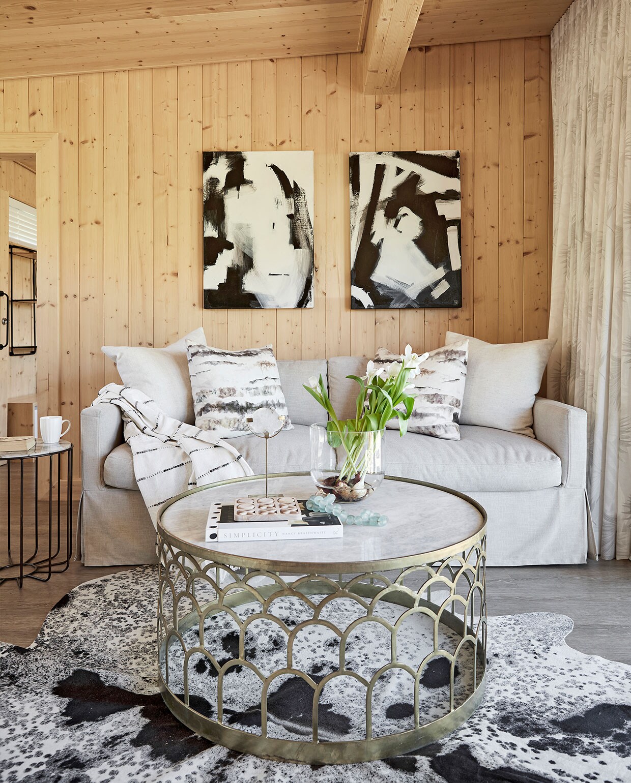Bijzettafel Weylandts. Slaapbank Giraffe Designs. Plaid Woolworths. Kussens Oooh Interiors. Grafisch kunstwerk Vicky Sanders. Koeienhuid African Leather and Skins. Salontafel Coricraft.