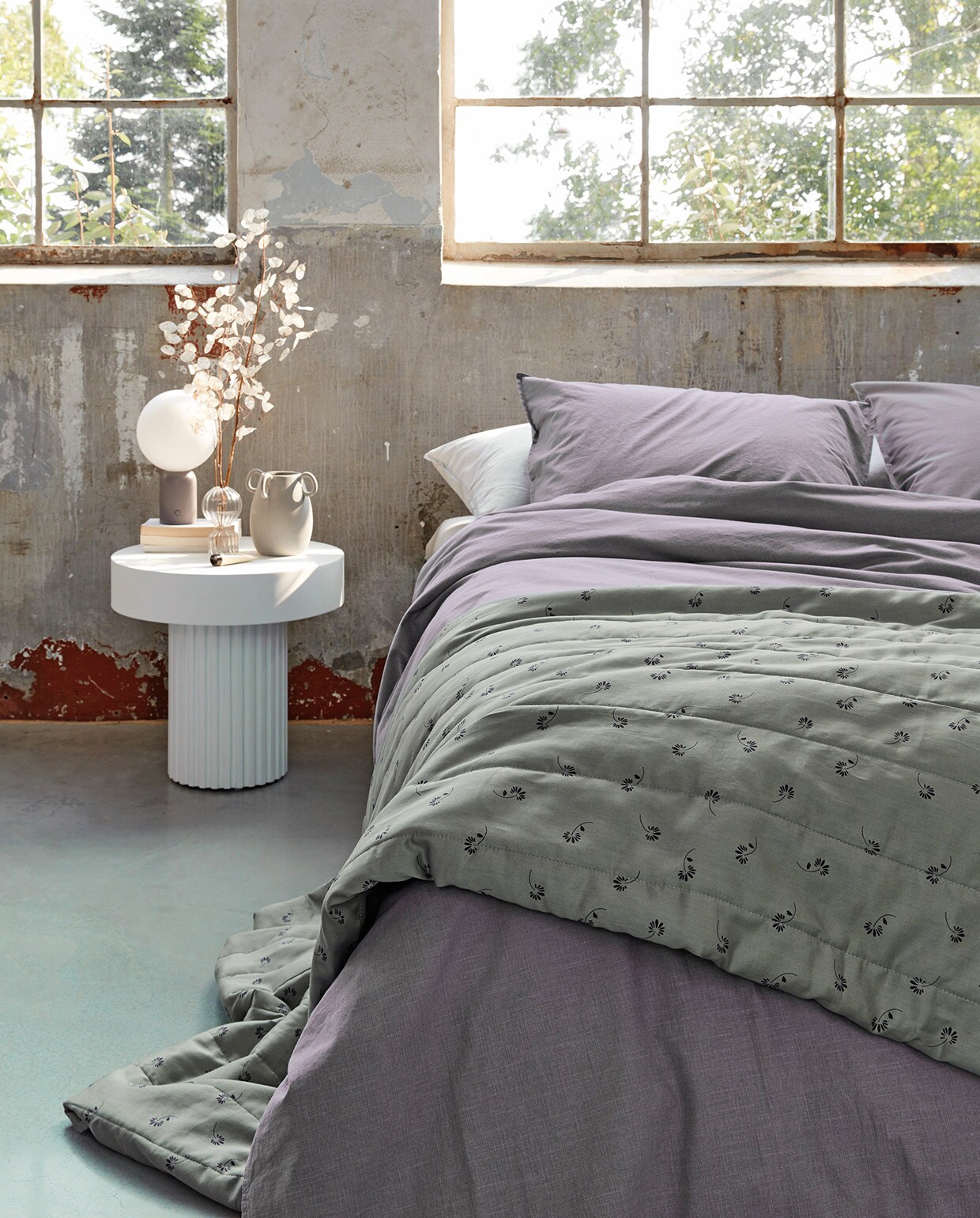 Katoenen dekbedovertrek Natural Stone in kleur lila, 140×200/220 cm, 200×200/220 cm en 240×200/220 cm (inclusief kussenslopen). Ook verkrijgbaar in kleur antraciet, donkergroen en terra. Op het bed katoenen Pattern quilt in kleur donkergroen (uni aan de binnenkant), verkrijgbaar in 180×250 cm en 260×250 cm. M.m.v. vtwonen.nl (nachtlamp van Bolia), loods5.nl/design (witte bijzettafel, glazen vaas). Overig privébezit.