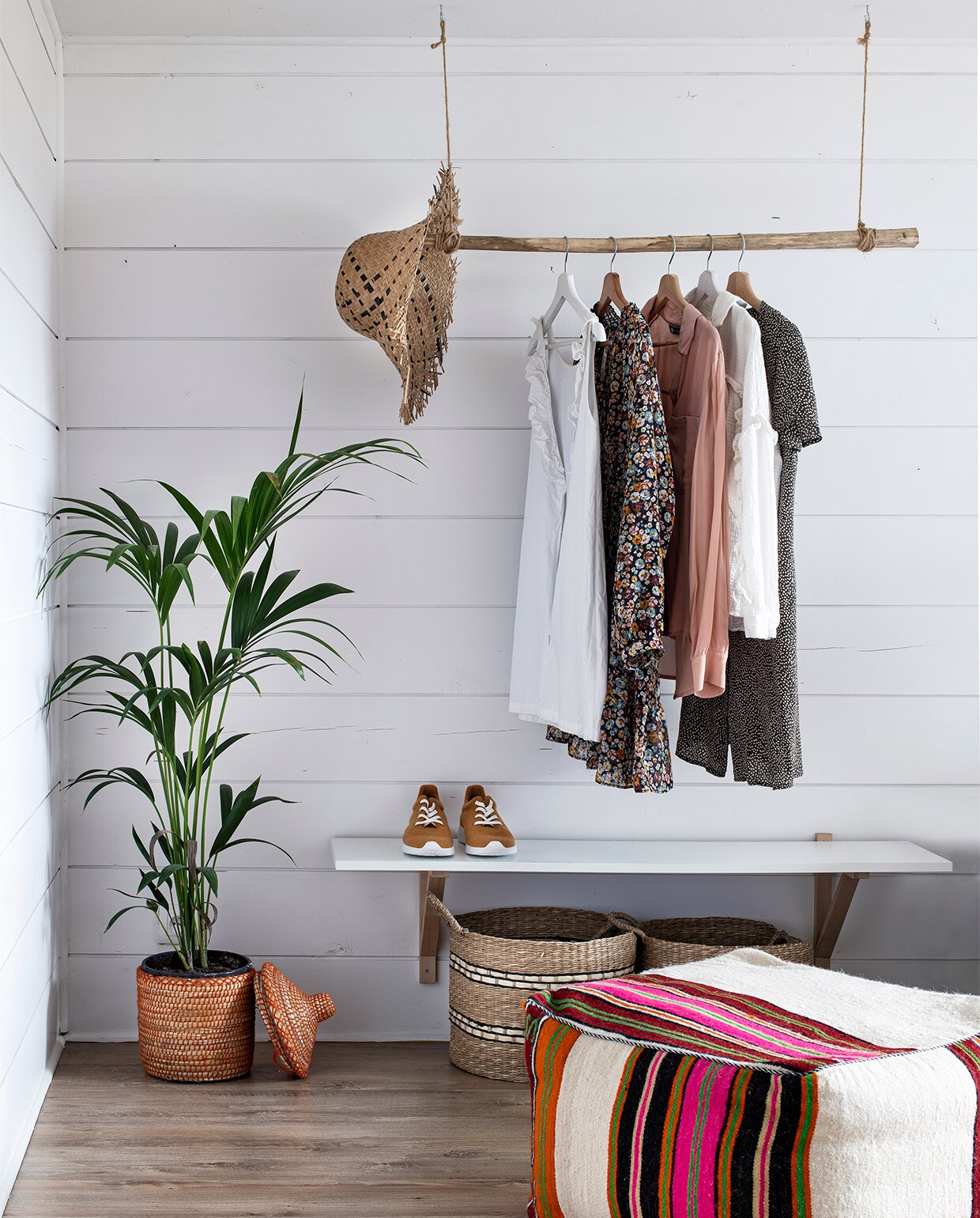 In de gastenkamers hangt een tak van sprokkelhout als kledingrek. Manden, plantenmand en poef Pompon Decoration Shop.