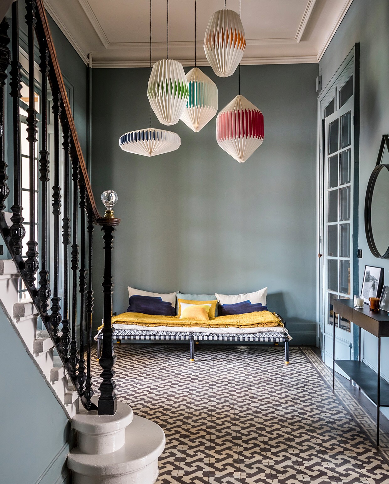 Muurverf Gray Stone van Little Greene. Papieren hanglampen Sentou. Charpoï-bankje, matras en plaid Le Monde Sauvage, kussens Jacques Design via La Gaité. Wandtafel AM.PM via La Redoute. Spiegel Hay. Kandelaar Sarah Lavoine. De originele vloertegels zaten al in het huis.