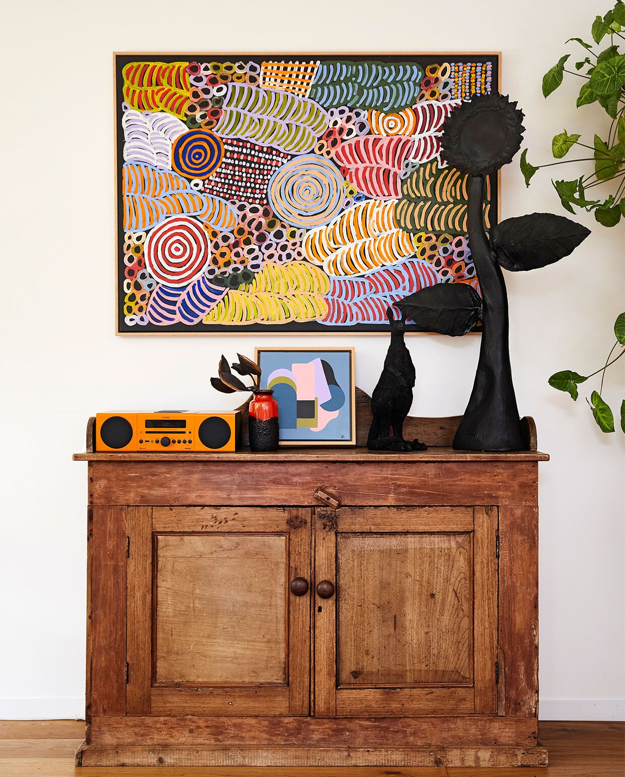 Antiek dressoir cadeau gekregen. Schilderij van Betty Mbitjana. Oranje sound system Yamaha. Vaas West-Germany. Geometrisch schilderijtje van Anna Cole. Zwarte kangoeroe Jumbled. Aardewerken zonnebloem zelf gemaakt.