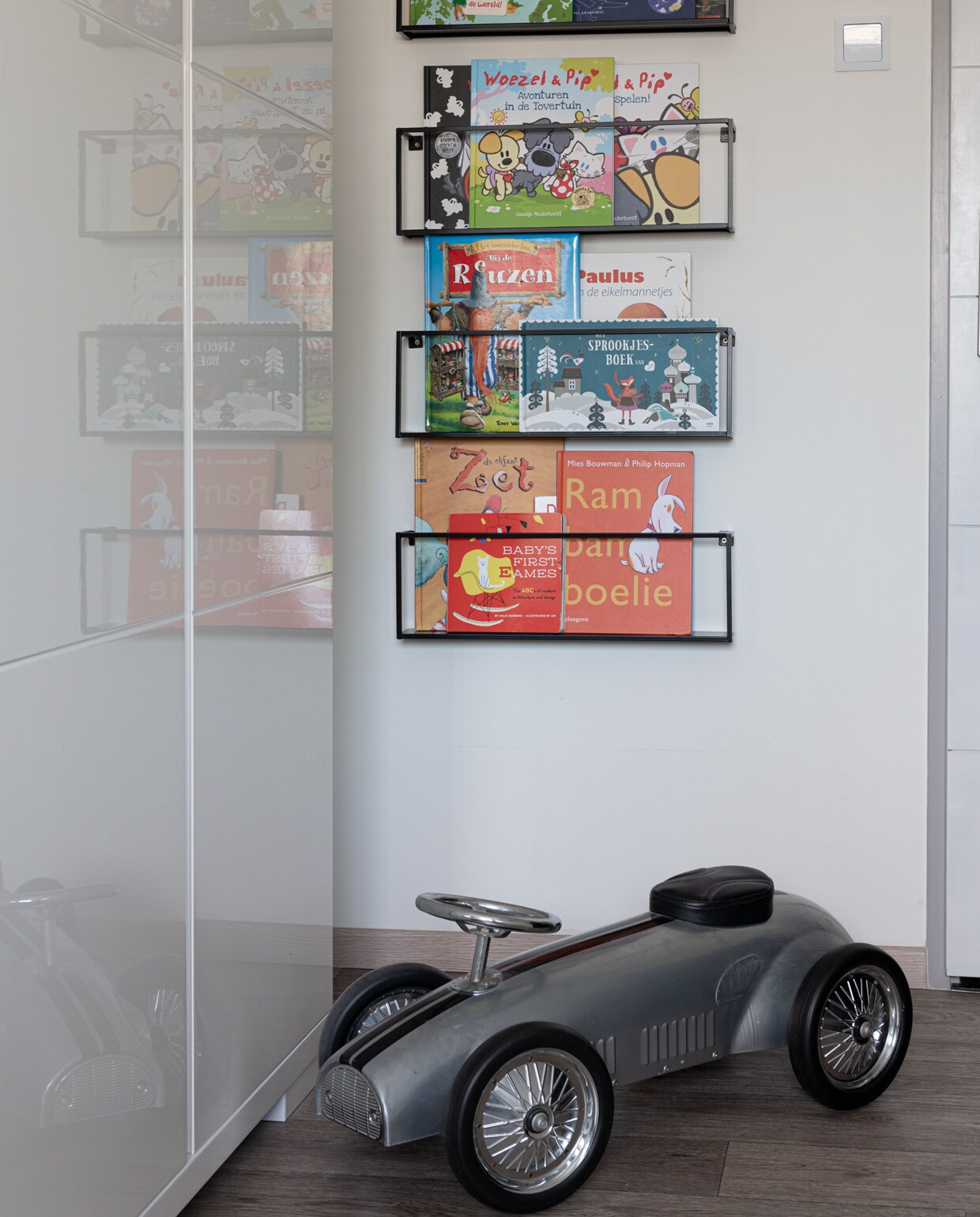 Grijze speelgoedauto en wandrek met kinderboeken