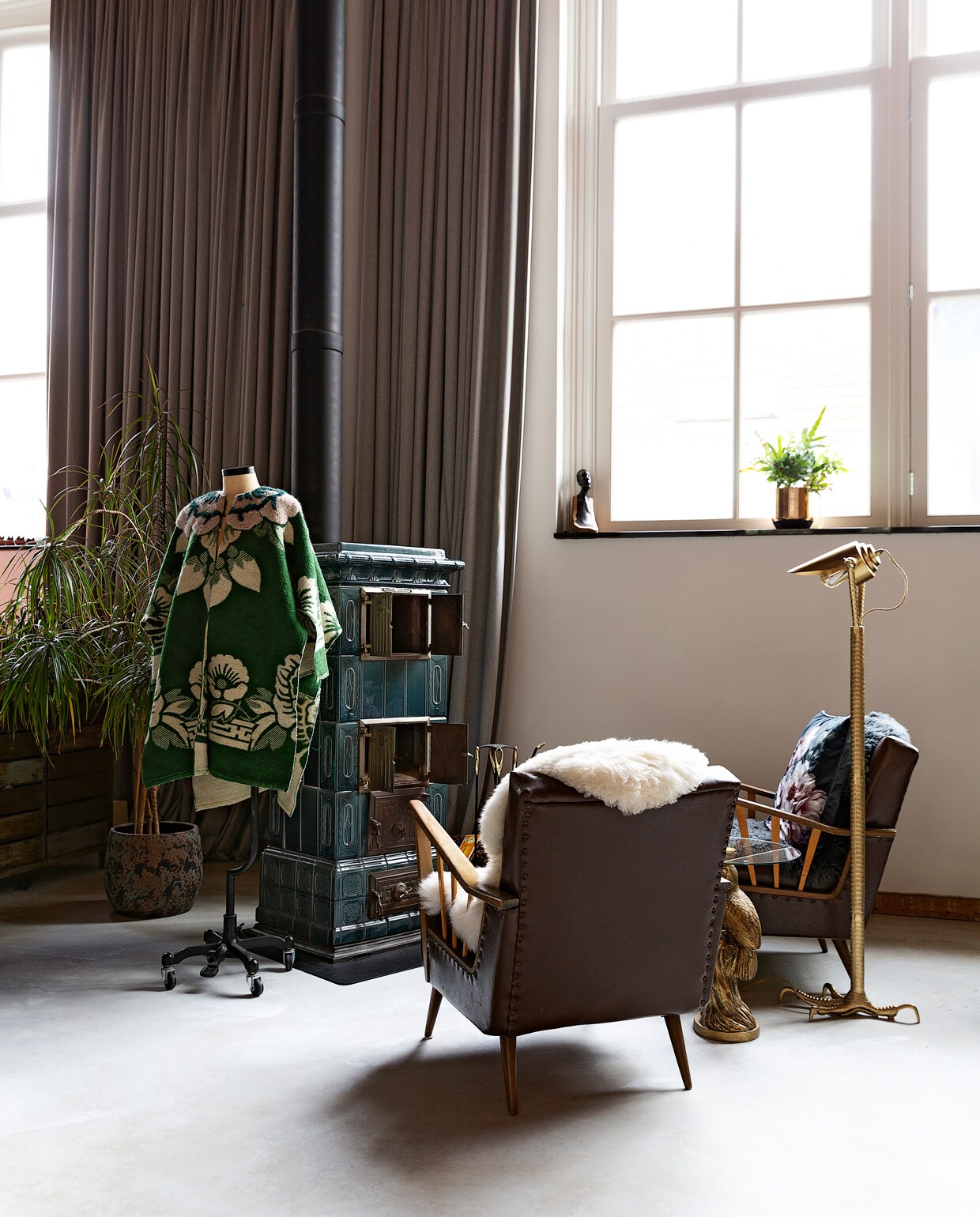Antieke tegelkachel Harrie van Gennip. De fauteuils zijn erfstukken. Jas eigen ontwerp voor Studio Wunderbar. Vloerlamp Falcon Dutchbone. Gordijnen zelfgemaakt.