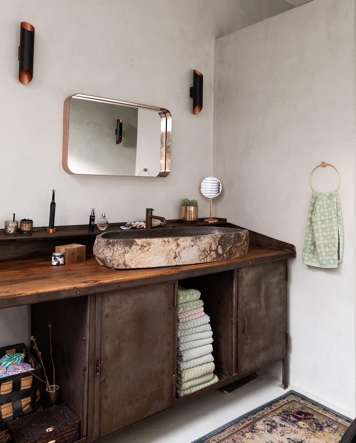 Oude werkbank Olde Looierij. Op maat gemaakte wastafel en kranen Hotbath, Meester Smeets. Spiegel Made. Wandlamp Agolada, Eglo. Vloerkleed Otto. Wanden en vloer Beton Ciré Pro (Zink), Trendstuc.