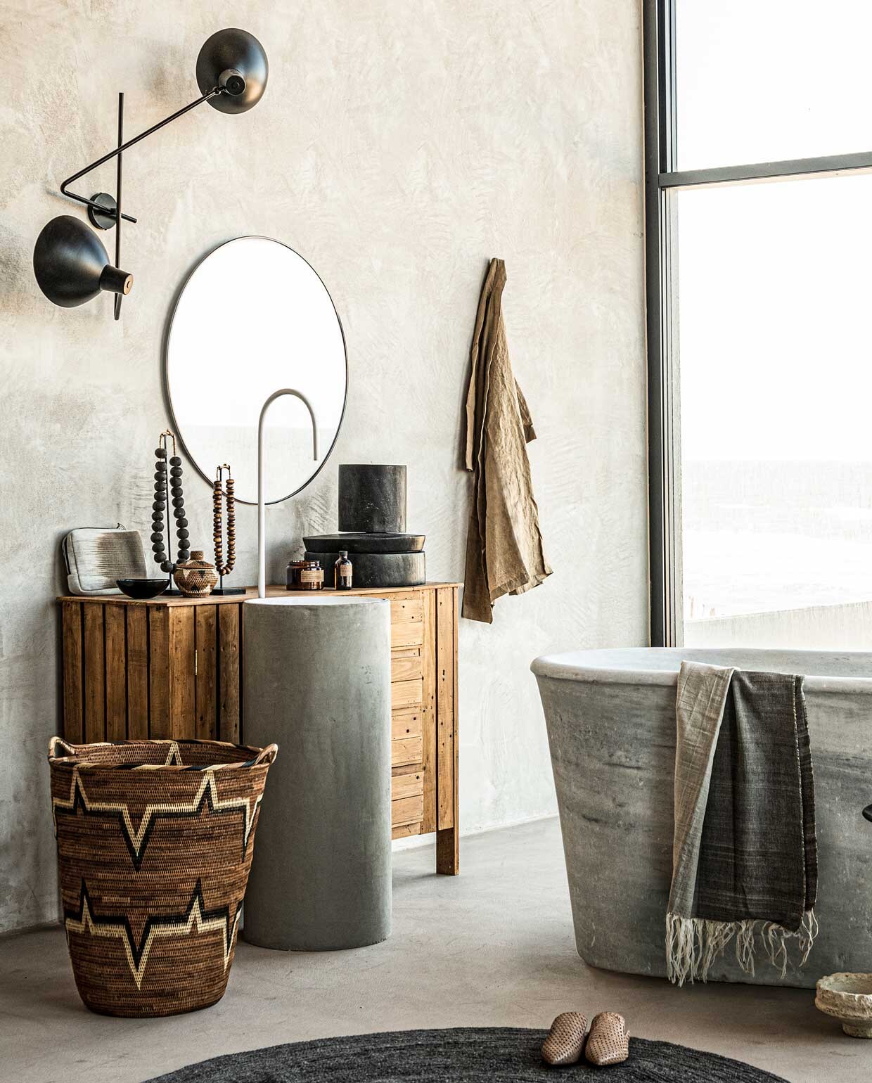 Spiegel Umbra Hubba Ø 86,4 cm € 150,-, wollen vloerkleed Bloomingville,Ø 140 cm € 155,- (vtwonen.nl). Op maat gemaakt wastafelmeubel van hout met waskom aan de voorkant Combitex, prijs op aanvraag (com-anders.nl). Mand Lalibu met handvaten, 53×59 cm € 459,-, witte graanpot van papier-maché op de grond, 11×23 cm € 49,- (couleurlocale.eu). Geurkaars op wastafelmeubel € 39,90, flesje voor geurstokjes € 27,90, bruin kommetje € 12,90,- (letoile.store). Marmeren bad € 6000,- (oudebouw­materialen.nl). Hamamdoek 100×250 cm € 130,-, stoffen etui € 45,- (badenbaden.nl). Linnen badjas € 39,99, slippers € 49,99 (hm.com). Grote kralenketting € 109,-, kleine kralenketting € 79,- (o-live.nl). Overig privébezit of bezit van de locatie (republiekbloemendaal.nl).