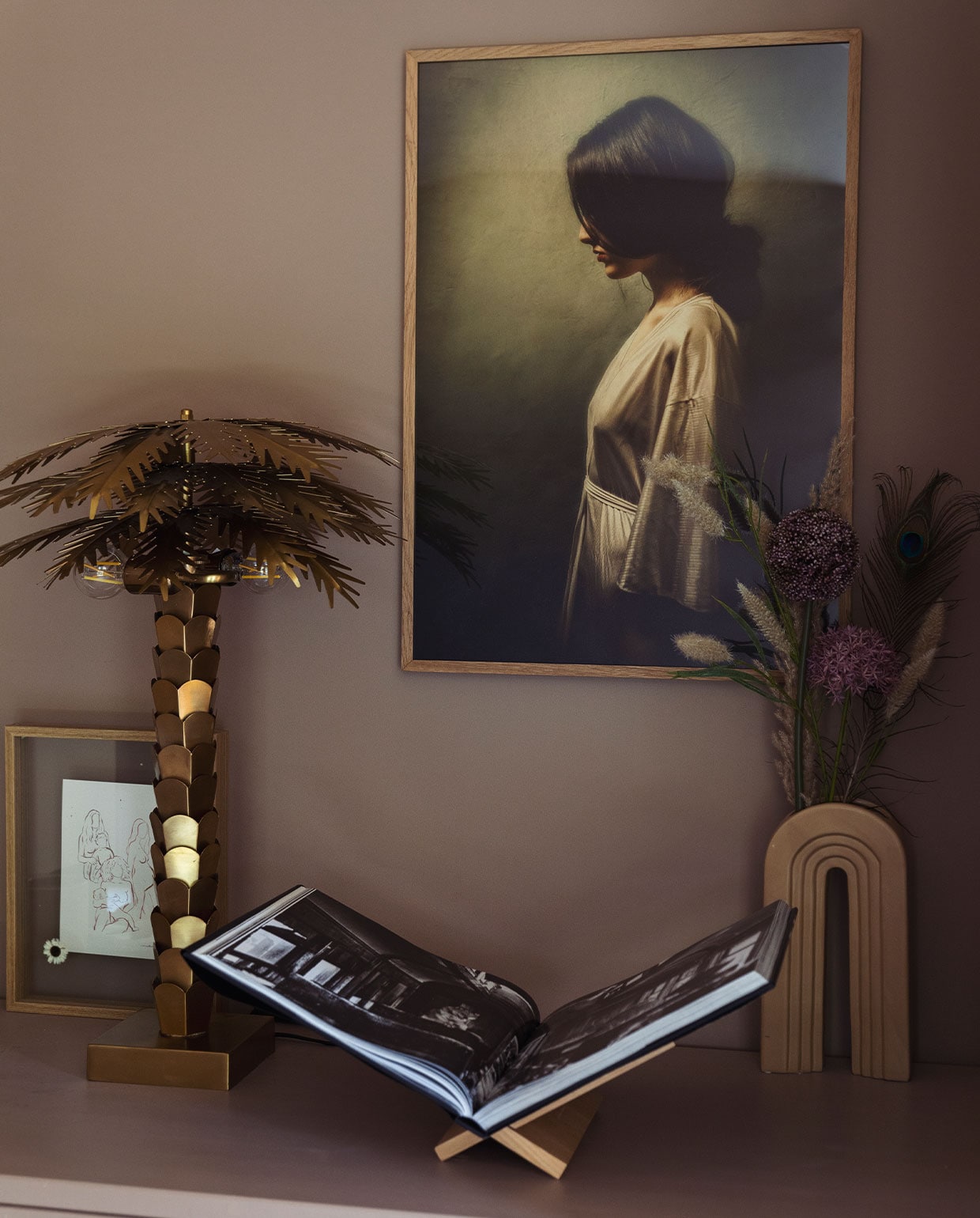 Schilderij Werk aan de Muur.Tafellamp palmboom HKliving. Fotolijstje Amber de Vreng. Vaas Karwei. Boekenstandaard Zara Home.