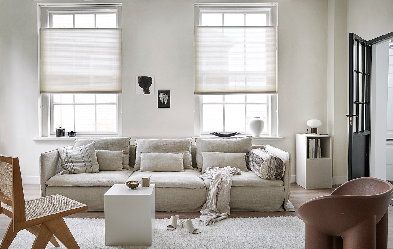 Lichtdoorlatend plisségordijn in kleur Linnenbeige (18074) vanaf € 204,39. m.m.v. karwei.nl (vtwonen EVC vloer in kleur Oat), ikea.nl (bank Söderhamn), bemz.com (linnen zetelhoes), zarahome.com (linnen plaid, zwarte schalen, witte vaas), stories.com (schoenen), aimetestudio.com (houten stoel Pierre), puurdesign.nu (bruine stoel Roly Poly van Driade), casagitane.com (rond kussen Tronc), newworks.dk (tafellamp), bauwerkcolour.com (muurverf in kleur Mykonos). Overig privébezit.