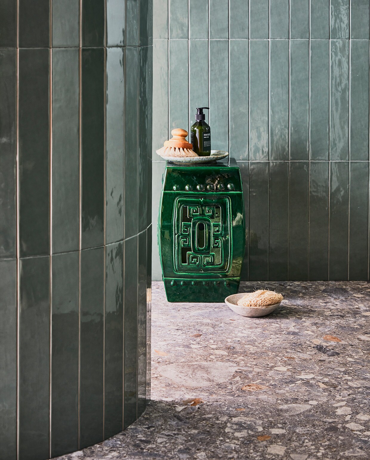Wandtegel Marrakesh, kleur Army Green, glans, 6,5×40 cm. Vloertegel Composite, kleur Multicolor, 120×120 cm.M.m.v. polspotten.nl (keramieken kruk), hm.com (handwas Meraki), weldaad.com (marmeren schaal).