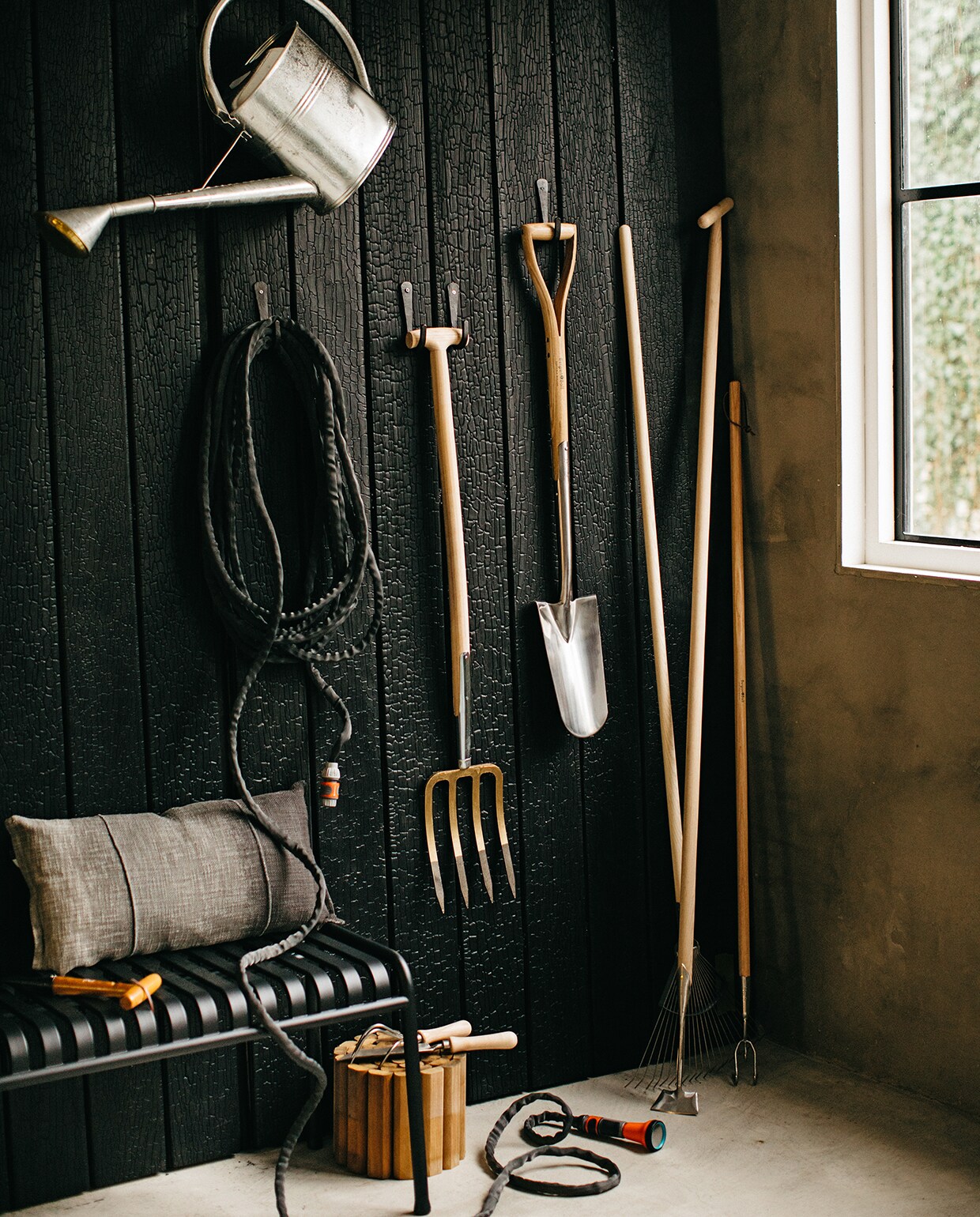 Wand bekleed met Marugame planken van gebrand Accoya hout (zwarthout.com). Haken voor gereedschap (loods5.nl). Gieter verzinkt, 8 liter (wiltfang.nl). Tuinslang Liano van Gardena (fonq.nl). 4-tands spitvork (gamma.nl). Verplantspade, schoffel, grashark, cultivator, handcultivator, onkruidschepje (wiltfang.nl). Houten rolborder (hornbach.nl). Tuinbank Palissade van Hay (fonq.nl). Plantstok (praxis.nl). Kussen (loods5.nl).