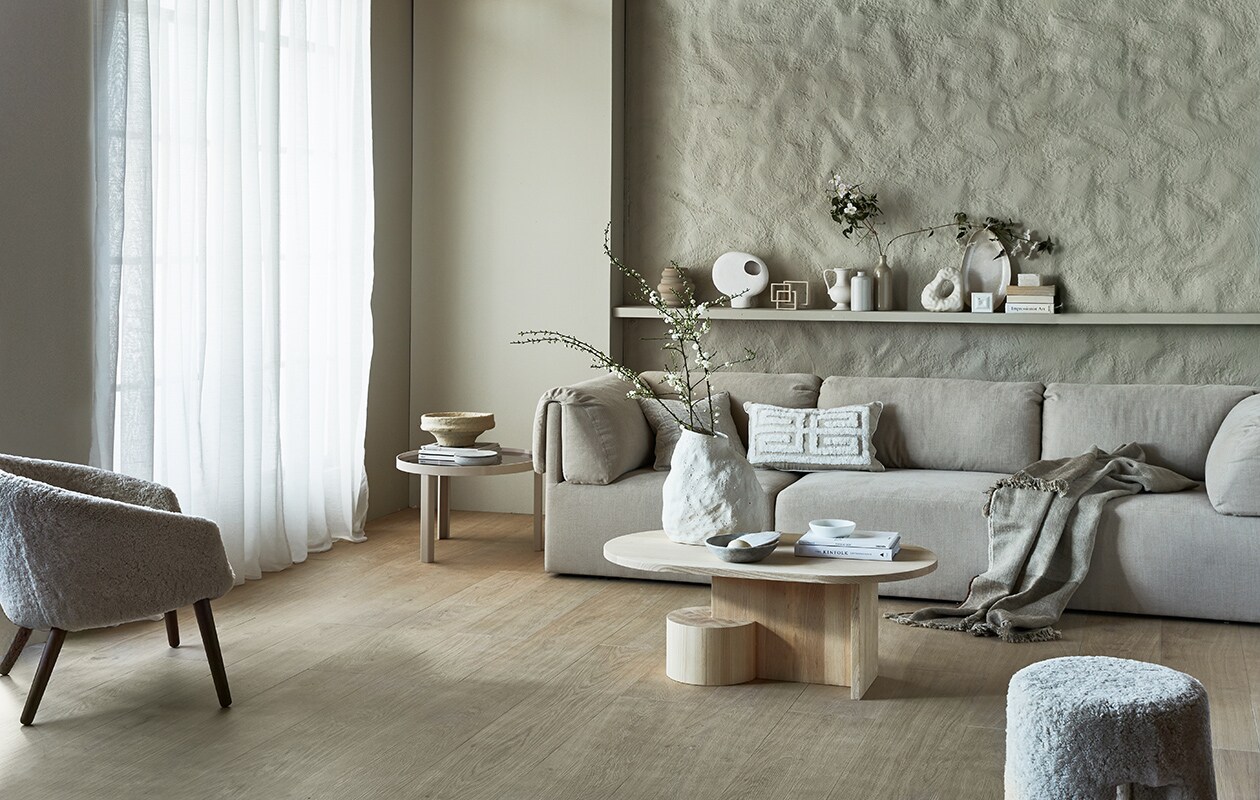Gordijn Frost, wit, half transparant, met plooi, 270×140 cm (hxb) € 42,99.M.m.v. karwei.nl (muurverf Warm Grey van vtwonen), vtwonen.nl (vloertegels Blancs Naturel van vtwonen, salontafel Insert van Ferm Living, vaas Vulca van Ferm Living, bijzettafel Cedric van Fest Amsterdam, boekensteun van Hay, zandkleurige geribbelde vaas Bloomingville, witte pot met deksel van Broste Copenhagen), nordicnew.nl (bank van Gubi), designtales.nl (fauteuil en poef van Fredericia), luxurybynature.nl (kussens, vaas met rond gat), studio-yen.com (sculptuur van vierkanten), weldaad.com (marmeren schalen en papier-maché schaal), couleurlocale.eu (plaid), hm.com (schaal op plank), neeflouis.nl (vintage flesvazen).
