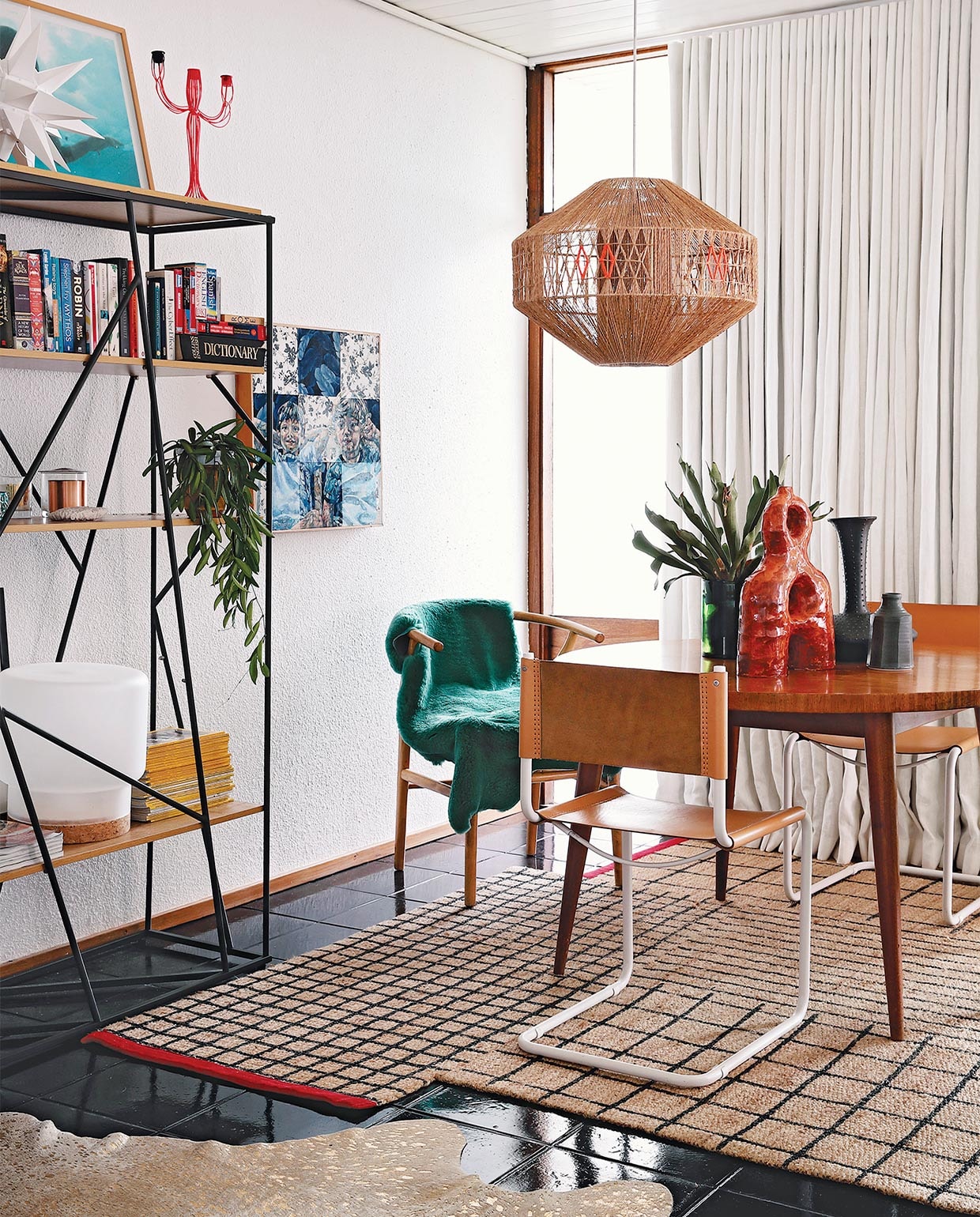 Vintage eettafel via Tonic Design. Stoel Wishbone Carl Hansen &amp; Son, overige stoelen Pezula Interiors. Groene schapenvacht Woodheads Cape Town. Rood, keramieken kunstwerk Ben Orkin, overige keramiek Anthony Shapiro. Hanglamp lokaal gekocht, die Kerryn versierde met oranje draad. Vloerkleed Ikea. Wandkast Mobelli. Witte ster Folha Plant Shop. Oranje kandelaar After Noah. Tafellamp Sinnerlig Ikea. Kunstwerk van Varenka Paschke. Overig onbekend.