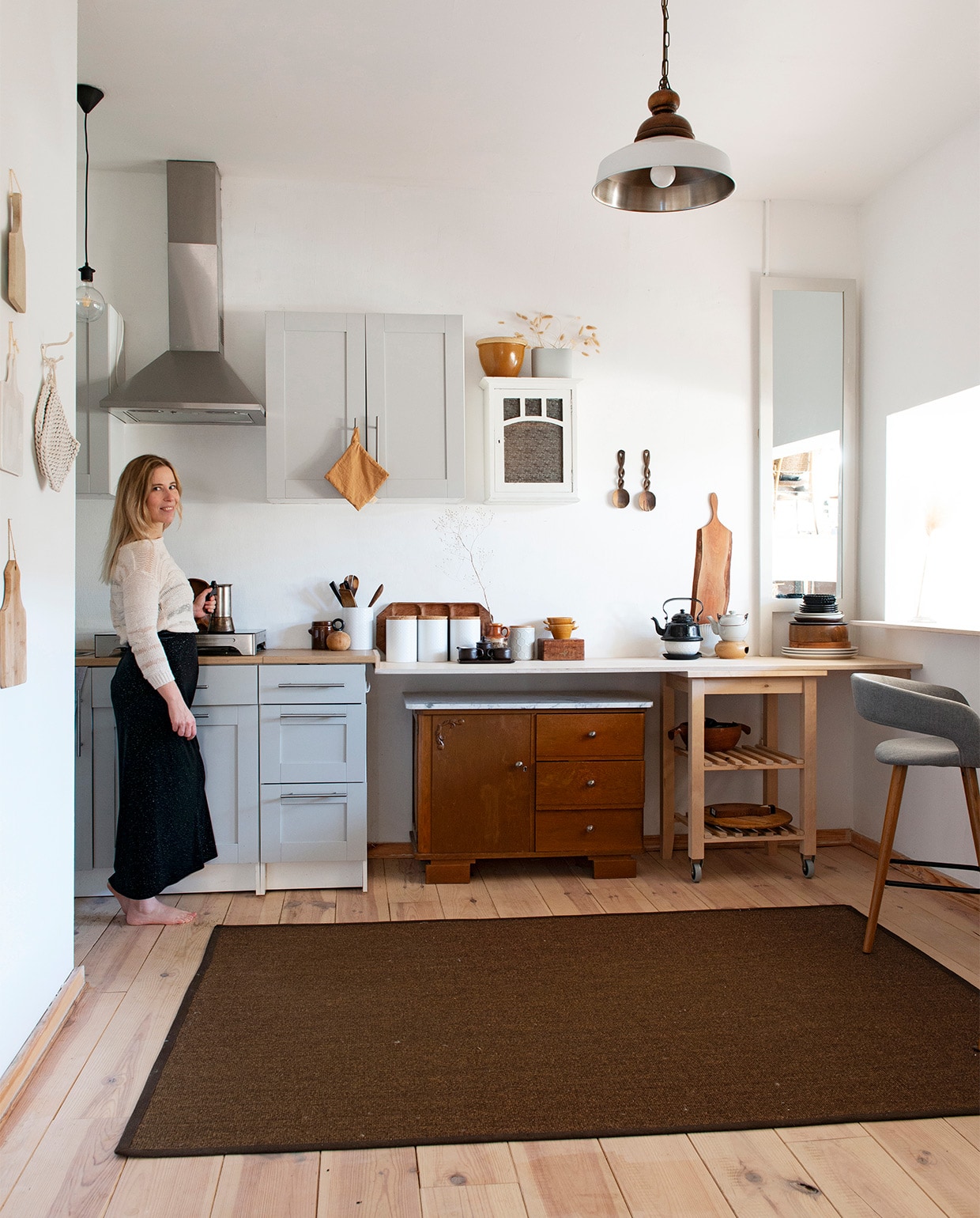 Witte voorraadbussen en zelf grijsgeverfde spiegel Xenos. Houten bar en verlengd keukenblad Woodchuck, lichtbruine lap Home by Door, droogbloemen Dreamlink via wish.com, barstoel Westwing Now, wit vaasje Edelman. Lamp vintage, samengesteld uit twee lampen, overig tweedehands van onder andere Rataplan. Herkomst vloer en sisal kleed onbekend.