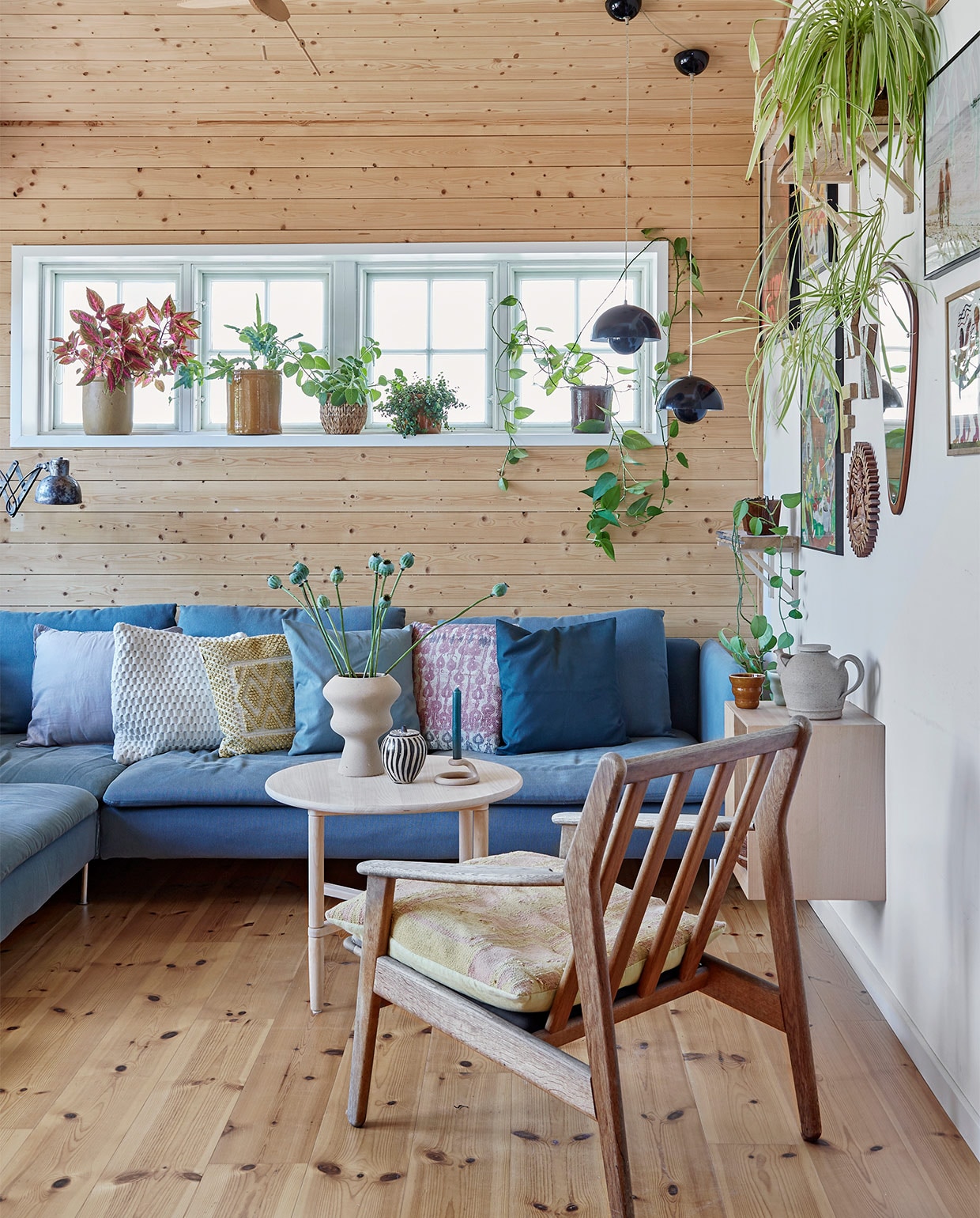 Blauwe bank Ikea. Kussens Au Maison en Madam Stoltz. Stoel en stoelkussen erfstukken. Ronde salontafel en hangend kastje DBA (Deense eBay). Beige vaas Ilva. Zwart-witte vaas, theepot en spiegel kringloop. Kandelaar Anthropologie. Wandlamp Leben CPH. Bloempotten voor het raam erfstukken en kringloopvondsten. Hanglampen Flowerpot &amp;Tradition. Aan de muur foto’s van reizen en kunst van een galerie in Ebeltoft. Wandplank zelfgemaakt. Overig onbekend.