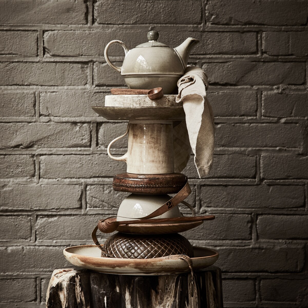 Theepot, stenen siervorm op staander, lunchbord, klassieke theemok uit set met theepot, houten bordje, soepbord met ruitpatroon (loods5.nl). Meetlint (harlequin-lisse.biz). Kleine houten lepel uit set met bakje, linnen theedoek (hm.com). Stenen voet (thewunderkammer.eu). Mok met kleurverloop van Wonki Ware (couleurlocale.eu). Gevlekt bord van HK Living (vtwonen.nl). Grote houten lepel HK Living (mooistoerwonen.nl).