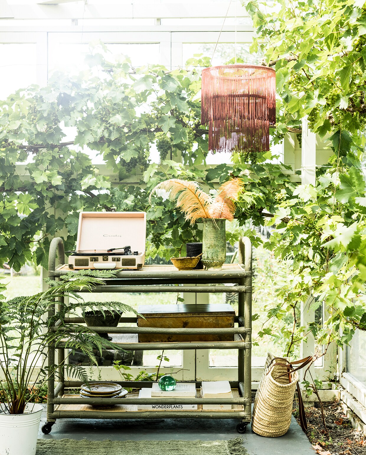 Franjeband met gradient effect (aboeken.nl). Trolley van HKliving, linnen vloerkleed, 155×215 cm (villajipp.nl). Groene borden en kommen uit de Tamegroute serie, saladeschaal Zigzag op voet uit de Tamegroute serie, vaas uit de Tamegroute serie, groen glazen object, rieten shopper (householdhardware.nl). IJzeren kist (newroutz.nl). Platenspeler van Crosley (urbanoutfitters.com).