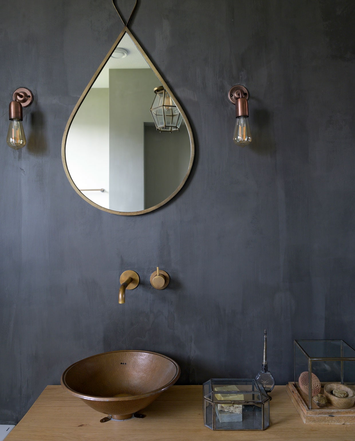 Badkamerwand kleur Graphite met zeer matte vernis Carte Colori. Spiegel Casa Vivante. Wandlampen Etsy. Wastafel op maat gemaakt door een meubelmaker. Kraan in aged brass Hotbath. Wasbekken Sahara Shop. Vitrines Casa Vivante.
