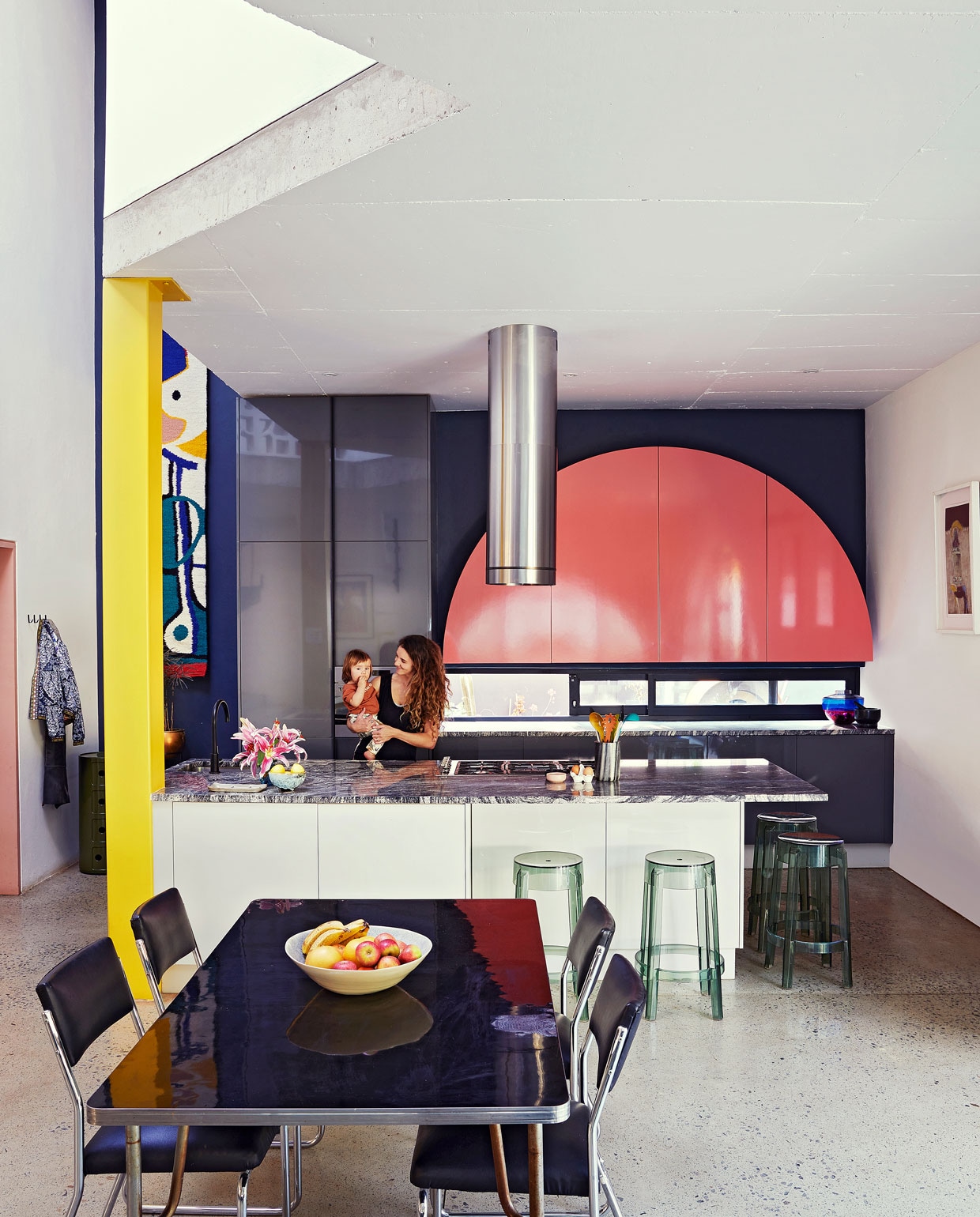 Keuken ontworpen door Gregory Katz via ProReno Kitchens, met werkblad van Namibisch graniet International Slate Sales. Vloer gepolijst beton World of Decorative Concrete. Groene bijzettafel Componibili, barkrukken Charles Ghost en blauw-roze vaas Shibuya Kartell. Eettafel en chromen buisstoelen vintage. Fruitschaal Wonki Ware. Zwarte haken Leroy Merlin. Wandkleed Renée Rossouw.