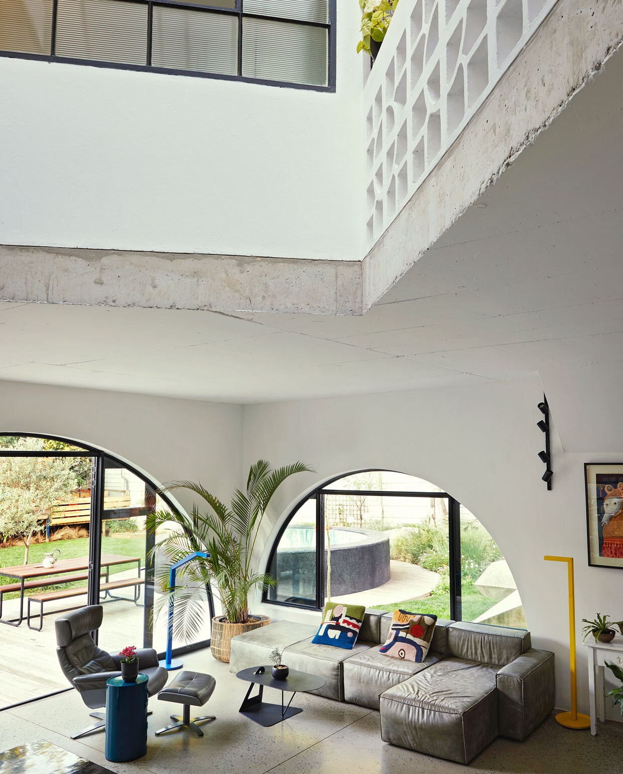 Vloer gepolijst beton World of Decorative Concrete. Zetel Weylandts. Kussens Renée Rossouw. Blauwe bijzettafel Componibili Kartell. Rieten plantenbak Amatuli Artefacts. Blauwe en gele lampen Nick-Knack Lirio by Philips. Zwarte wandlamp Spazio. De witte sidetable is een antiek slagersblok met marmeren blad Marmernova. Overig onbeken