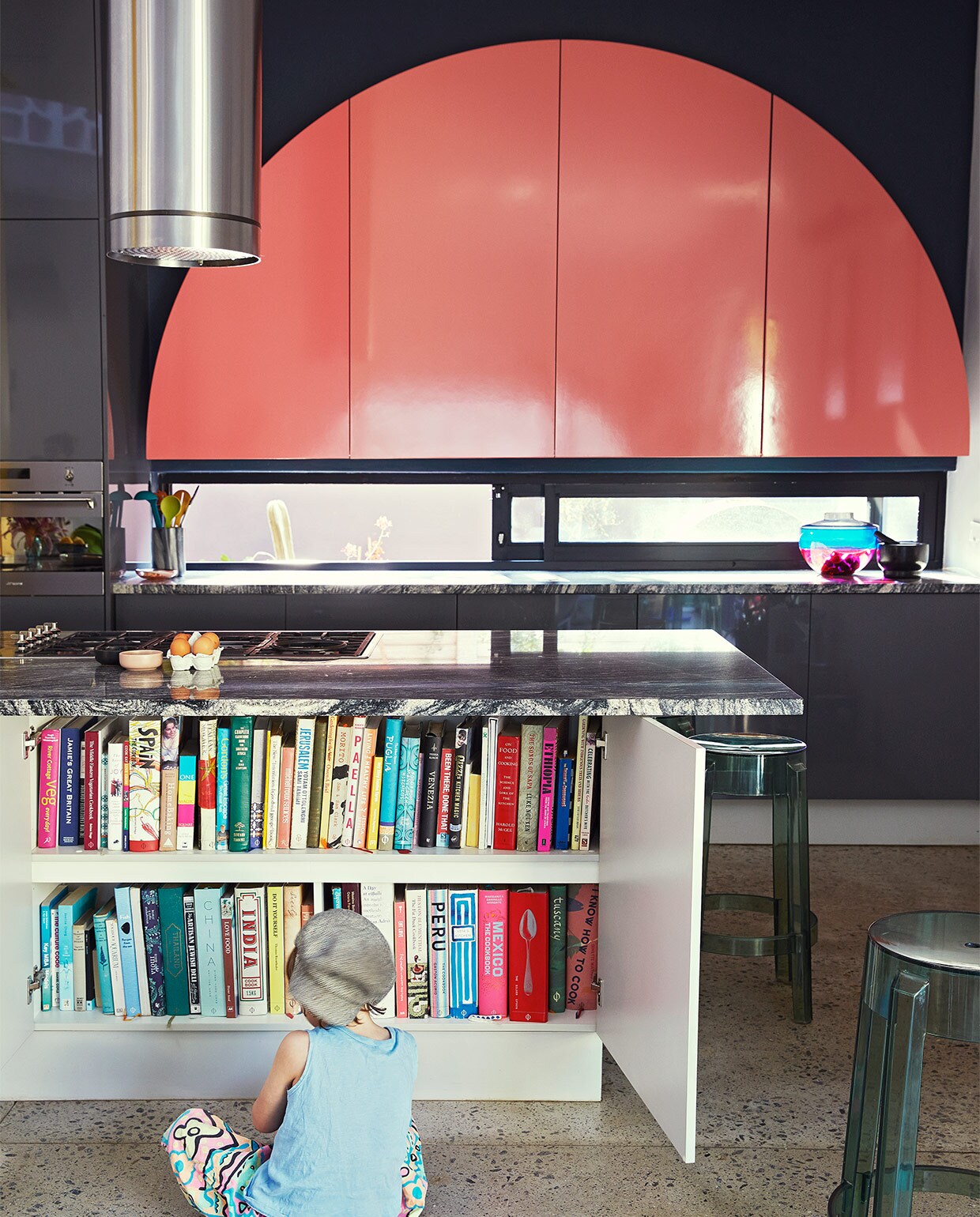 Keuken ontworpen door Gregory Katz via ProReno Kitchens, met werkblad van Namibisch graniet International Slate Sales. Vloer gepolijst beton World of Decorative Concrete. Barkrukken Charles Ghost en blauw-roze vaas Shibuya Kartell. Zwarte haken Leroy Merlin.