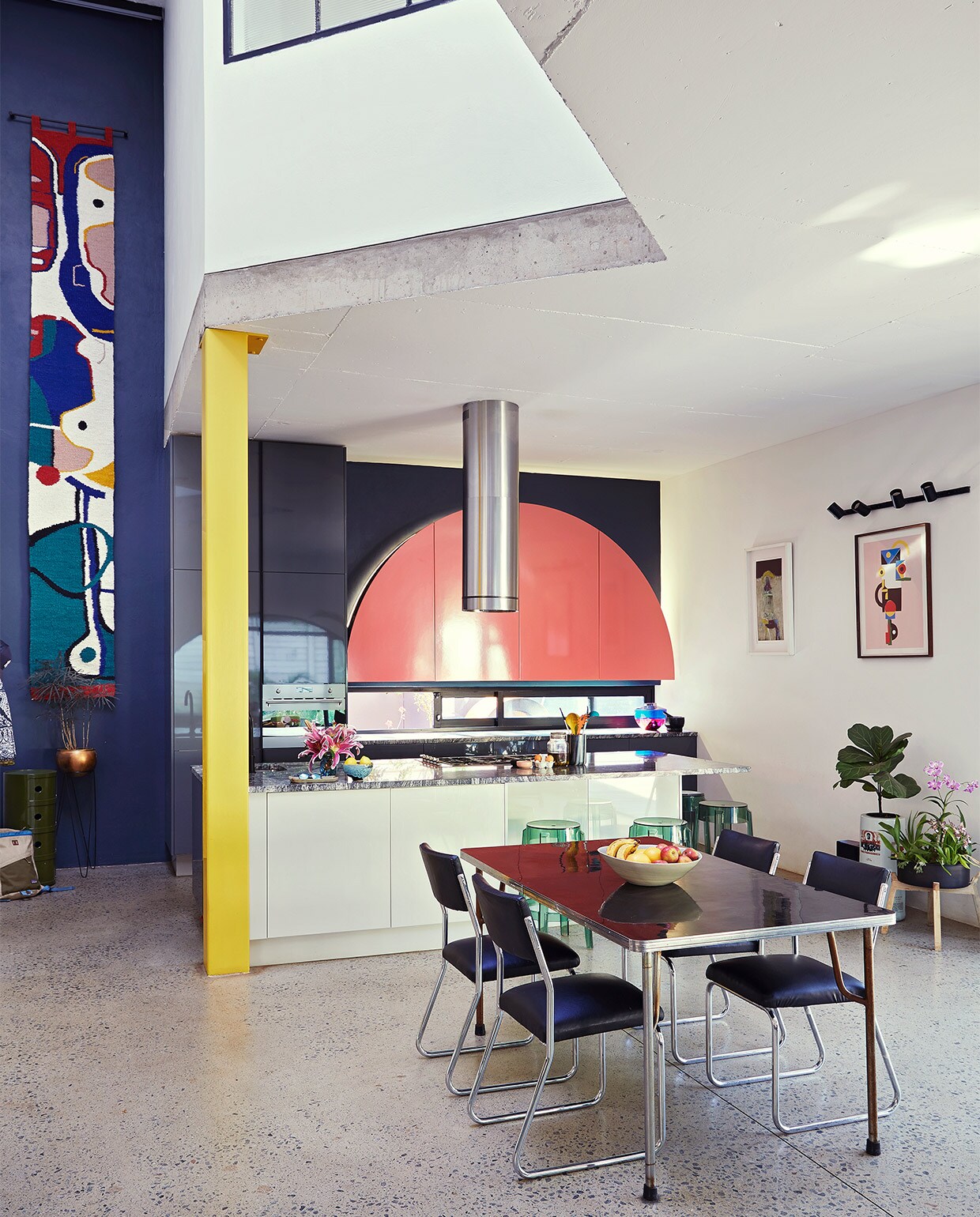 Keuken ontworpen door Gregory Katz via ProReno Kitchens, met werkblad van Namibisch graniet International Slate Sales. Vloer gepolijst beton World of Decorative Concrete. Groene bijzettafel Componibili, barkrukken Charles Ghost en blauw-roze vaas Shibuya Kartell. Eettafel en chromen buisstoelen vintage. Fruitschaal Wonki Ware. Zwarte haken Leroy Merlin. Wandkleed Renée Rossouw.