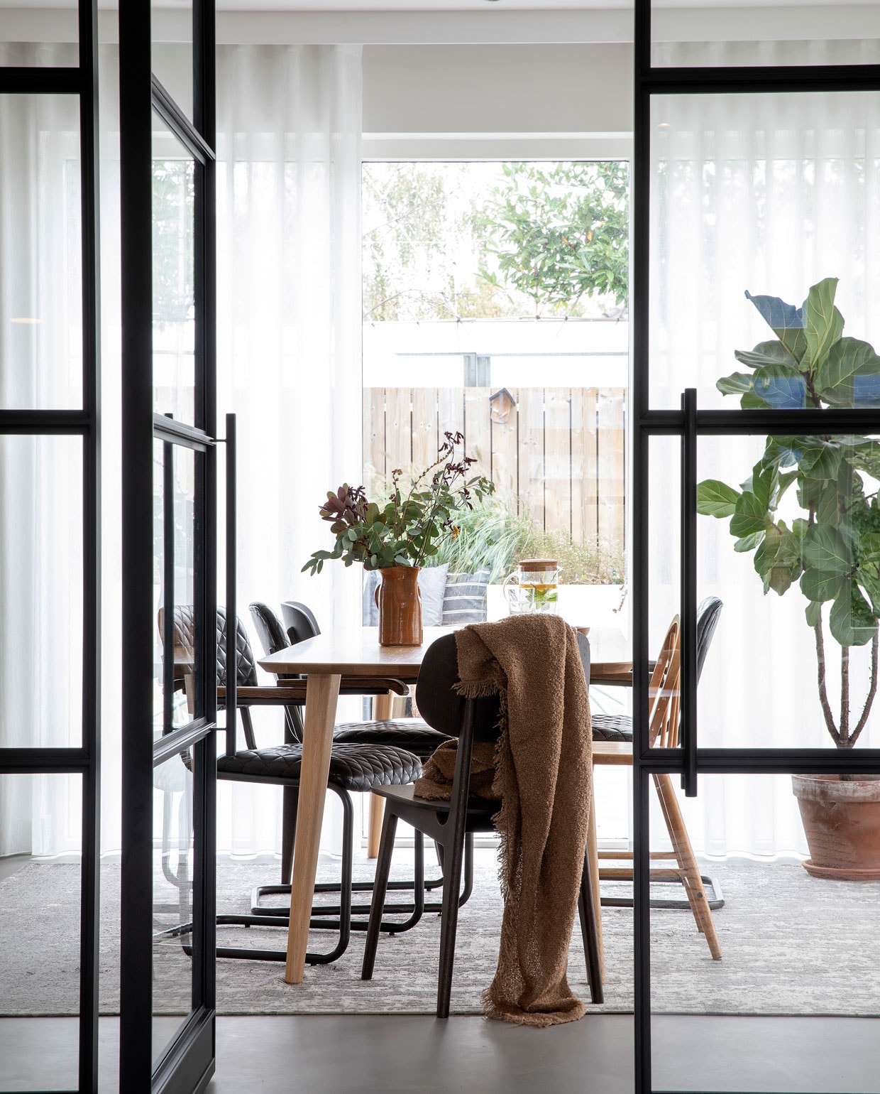 Deuren met stalen kozijn op maat gemaakt door Wout Jansen. Tafel Sav &amp; Økse. Stoelen By-Hoo. Hoge kinderstoel Ikea via Marktplaats. Vloerkleed Floorpassion. Plaid H&amp;M Home. Vaas van de kringloopwinkel.