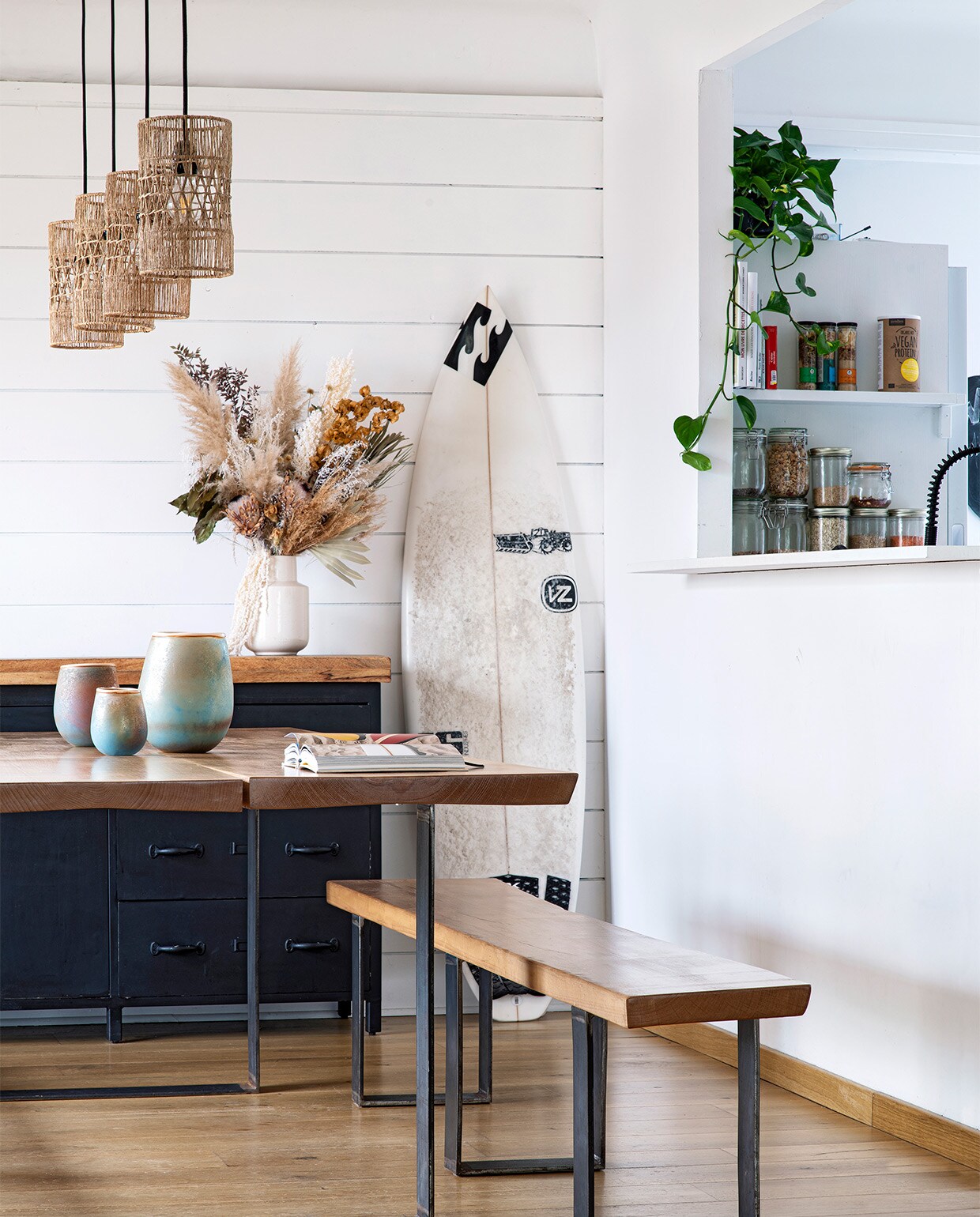 Houten tafel en bank door Sam gemaakt. Keramiek verzameld in Frankrijk. Grijze vaas Ikea. Droogbloemen Teepee Sauvage in Hossegor. Rotan lampen La Redoute. De surfplank was ooit van de Australiër Joel Parkinson, wereldkampioen surfen in 2012.