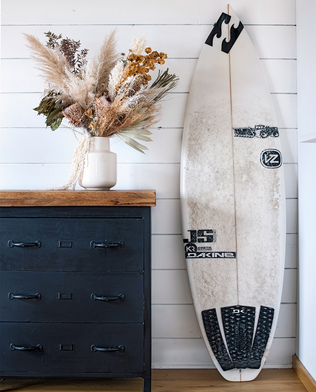 Houten blad op ladekast brocante van Biscarosse. Keramieken vaas Philippine Boho Factory, boeket droogbloemen Teepee Sauvage. De surfplank was van de Australiër Joel Parkinson, wereldkampioen surfen in 2012.