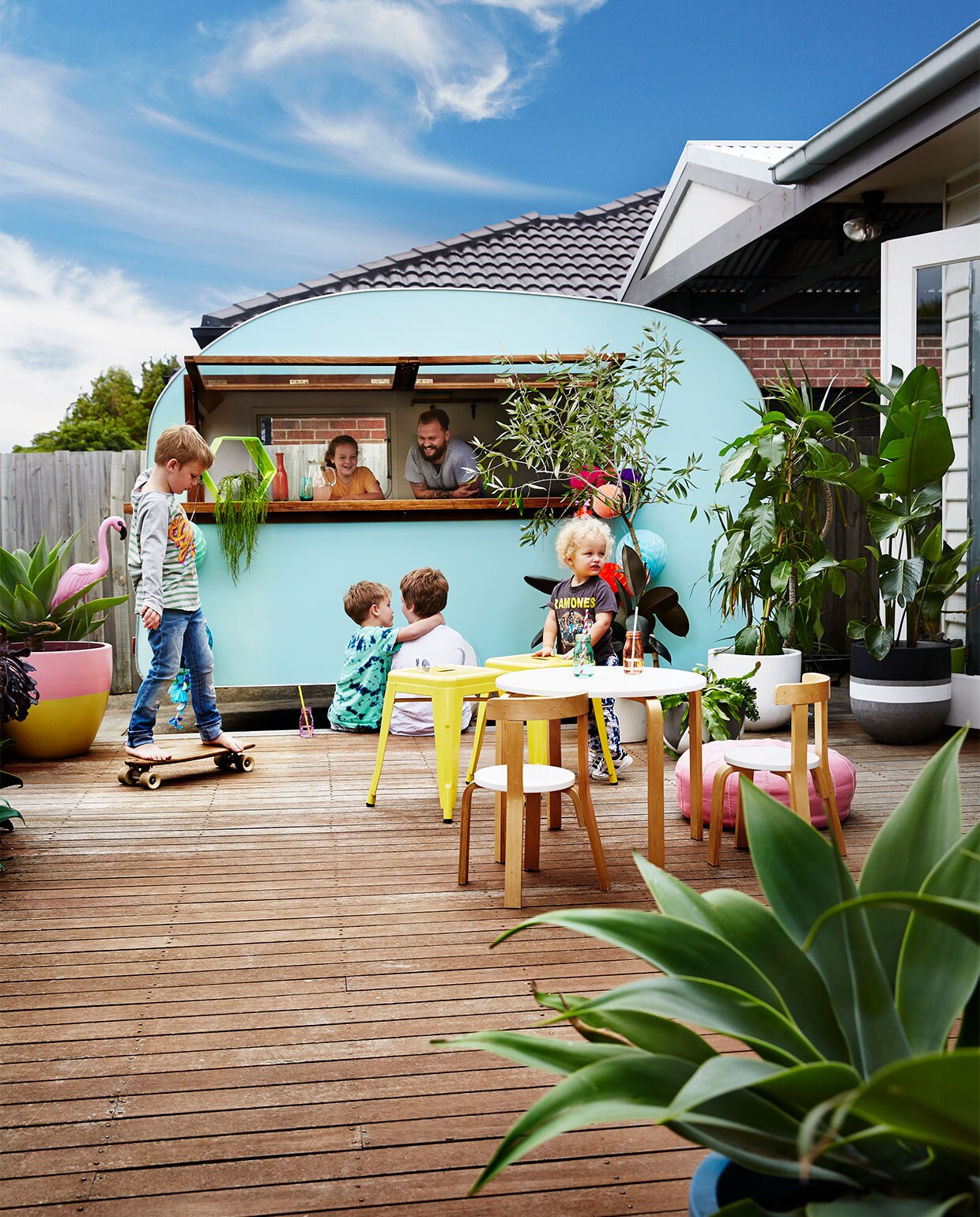 De achtertuin heeft een groot houten dek, waar een oude caravan dienst doet als barretje. Houten tafel en stoelen HipKids. Krukken Tolix. Overig onbekend.