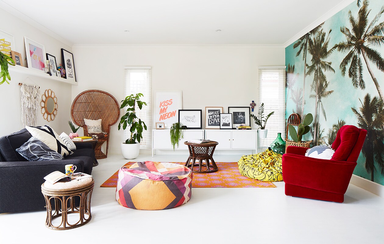 Palmbomen-behang Byron Bay Wallpaper. Yin-en-yangkussen, kussen Locals Only en regenboogkussen Kawaiian Lion. Grafisch zwart-witkussen Target. Macramé wandhanger Family Threds. Rotan bijzettafels en stoel gevonden op straat. Roze neushoornplantenpot Rice dk. Witte locker PS Ikea. Print XO Loneley Sea. Poef Pony Rider. XL bananenkussen Kip &amp; Co. Overig onbekend.