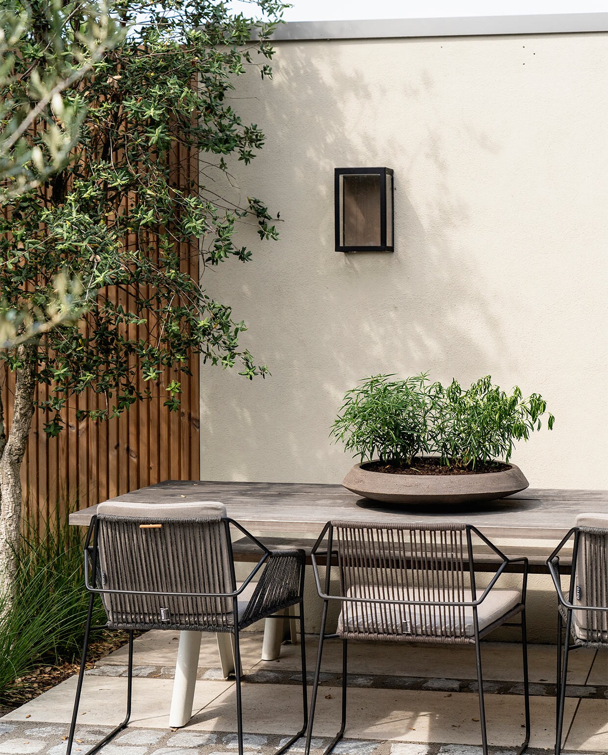 Tuintafel Skagerak via The Garden Store. Stoelen Oasiq Sandur. Bloempot Atelier Vierkant. Buitenverlichting In-lite.