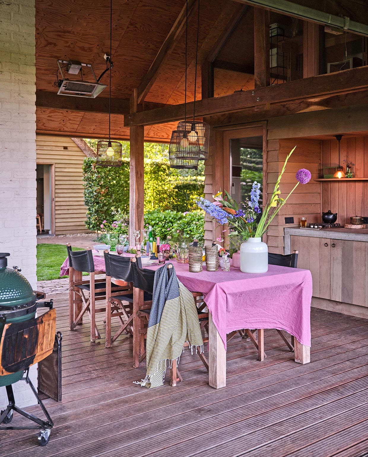 Lucas maakte de keuken in het tuinhuis zelf van wrc-delen, rode ceder. De lampen zijn vogelkooien die Carolien zwart heeft gespoten. Het roze tafellaken is een onafgewerkte linnen lap van de markt. Barbecue Green Egg. Hammamdoek Sissy-Boy Homeland. Regisseursstoelen Vervoort Meubelen. De vazen komen overal en nergens vandaan.
