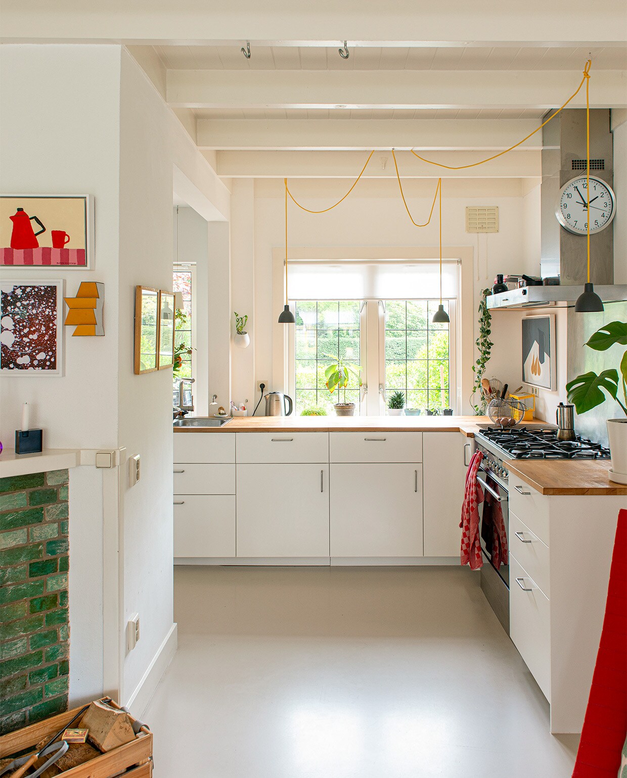 Keuken, plantenpot aan muur en bloempot op aanrecht Ikea, hanglampen Told Bold van Louis Poulsen, vloer Coaton in kleur RAL 2005-Y50R, kunstwerken boven aanrecht van Alessandra Taccia en Lon Pennock.