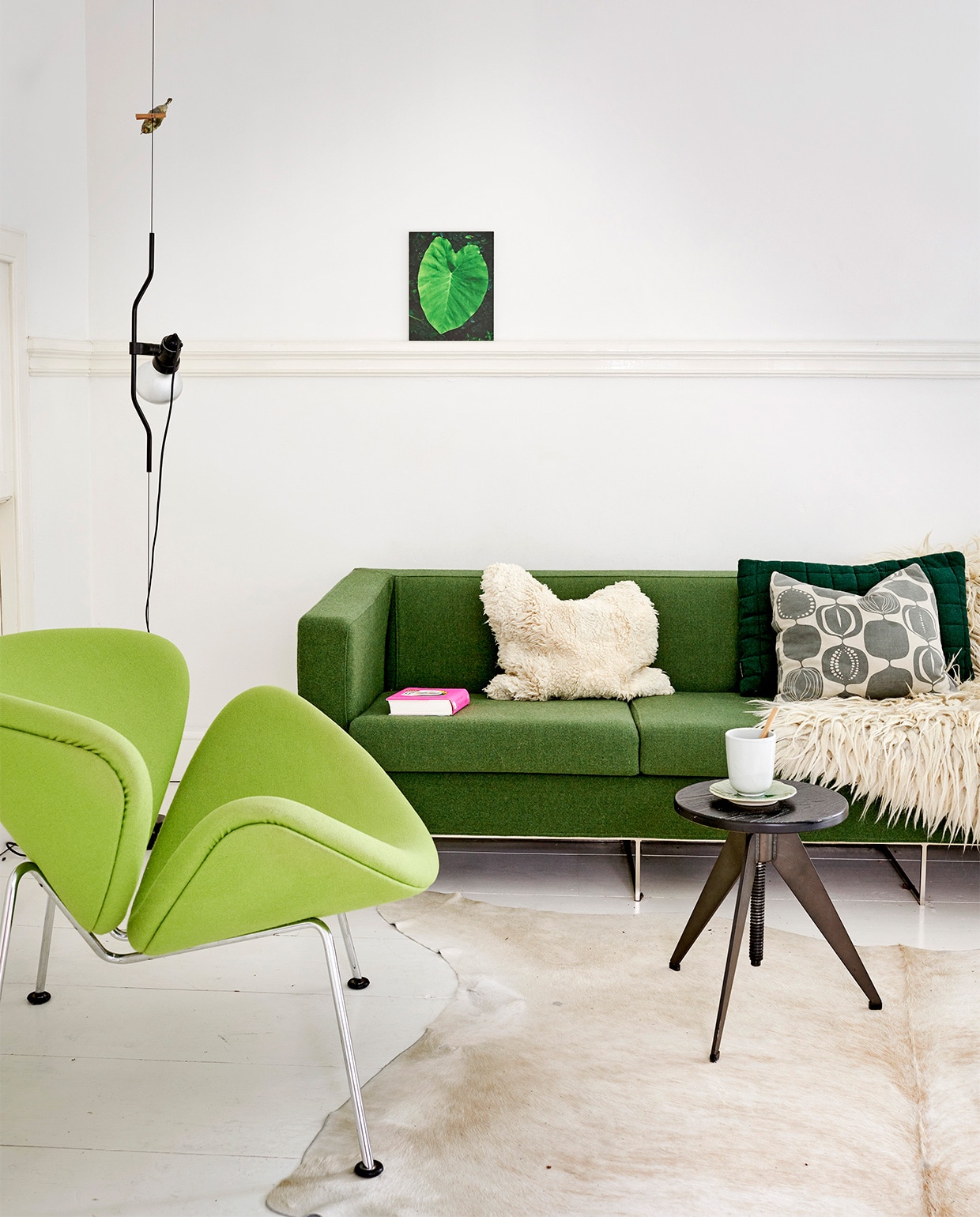 Bank gestoffeerd door Stoffeerderij Ahmad. Fauteuil Orange Slice van Artifort. Koeienhuid Pols Potten. Foto blad van Renate Schwarz. Vogel op knijper Jeffrey Zijlstra. Zwarte lamp Parentesi van Flos. Kussen met patronen en wollen nomadenkleed Sjakie’s. Herkomst overig onbekend.