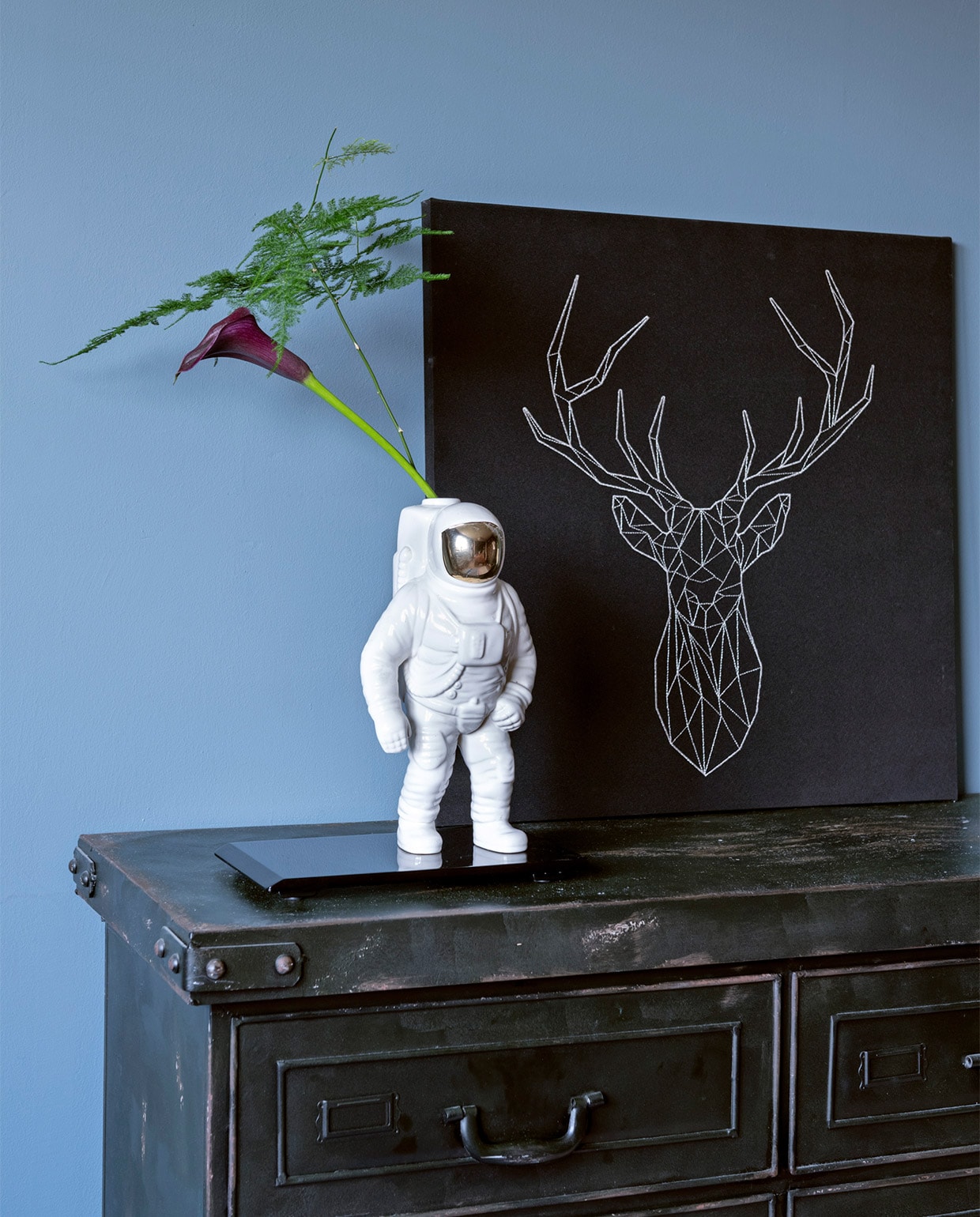 Muurverf Denim Drift van Flexa. Ladekast Loods 5. Vaas Astronaut van Diesel by Moroso. Zwarte onderzetter vintage. Herkomst hertenprint onbekend.
