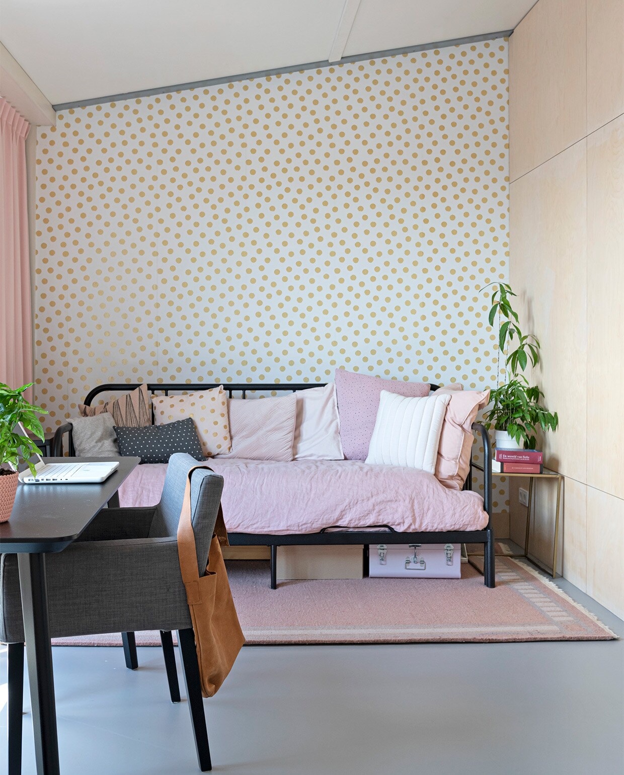 In de logeerkamer wandafwerking met berken-multiplex platen. Behang uit collectie Eijffinger + Rice. Vloer linoleum Walton van Forbo. Slaapbank, bureau, stoel Ikea. Dekbedhoes, kussens Loods 5. Vloerkleed tweedehands. Bijzettafel van Sissy-Boy Homeland. Kussens Loods 5 en Kwantum.