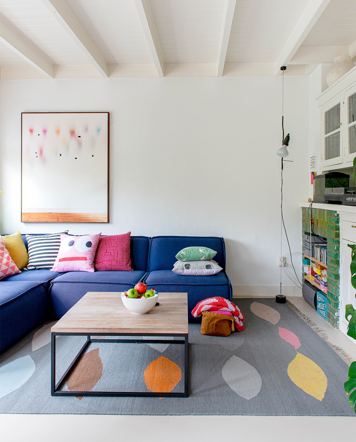 Bank Edge van Fest Amsterdam, kussens van diverse herkomst, fotografisch kunstwerk van Katja Mater via Galerie Heden, salontafel laten maken door smid, schaal Bebouwde Kom van Olav Slingerland, karpet Leaves van CarpetVista, in de hoek lamp Parentesi van Flos.