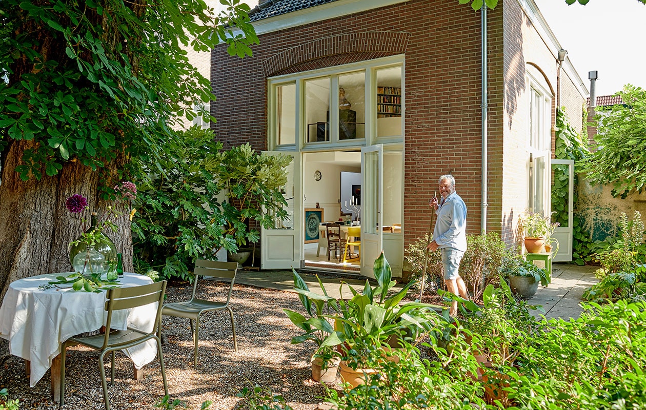 Ronde houten tafel tweedehands. Linnen tafelkleed MrsBloom. Stoelen Luxembourg van Fermob. Plant op de achtergrond: siergember (Hedychium gardnerianum), op de voorgrond Ficus Brown Turkey.