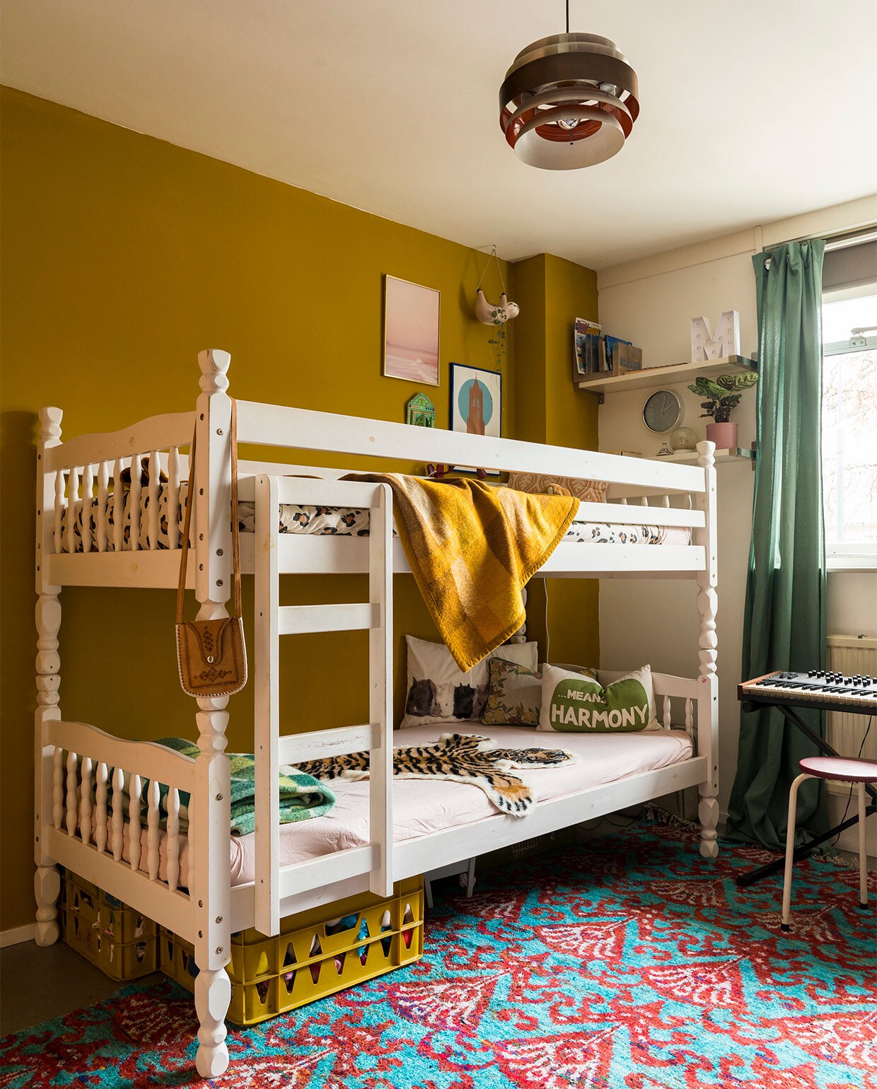 Verfkleur op de wand Komijn van Gamma. Bed via Marktplaats. Beddengoed en luiaard Kwantum. Gele en groene wollen dekens kringloopwinkel. Kussen met geel motief Auping. Roze print IrisDorine. Domtoren We are out of office. Kratten kringloopwinkel. Konijnenkussen Ikea. Kussen met Means Harmony H&amp;M Home. Gebloemd kussen kringloopwinkel. Tijger herkomst onbekend. Spiegeltje uit Marokko. Vloerkleed Marktplaats. Gordijn Kwantum. Wandplankjes Ikea. Letter M Hema. Klok herkomst onbekend. Hanglamp Marktplaats. Krukje kringloopwinkel. Synthesizer privébezit. Tasje herkomst onbekend.