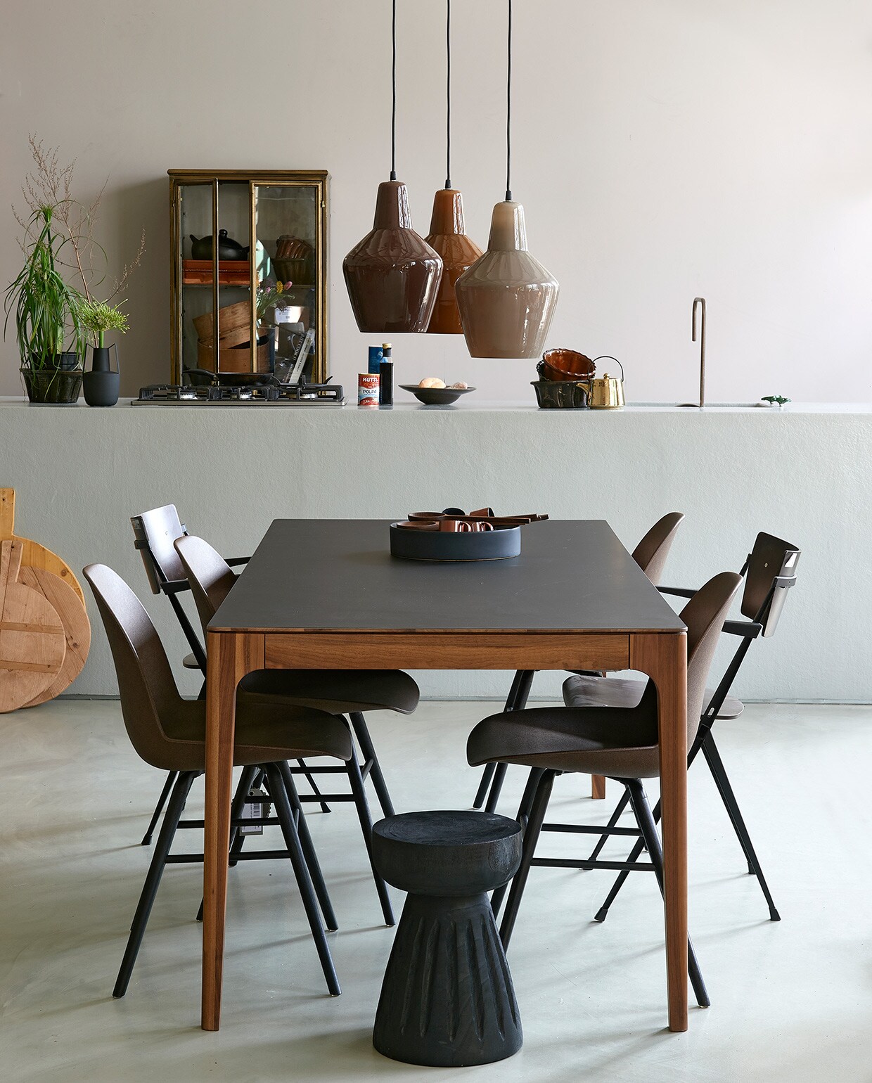 Op de wand matte muurverf Skin van vtwonen, 2,5 liter (karwei.nl). Tafel Rikke met zwart fenix blad en walnoten onderstel, 160x90x76 cm (lxbxh) (demachinekamer.nl). Koperkleurige vitrinekast Gertlush, 63,5×41,5×184 cm (bxdxh) , (dutchbone.com). Kuipstoelen Albert Kuip van gerecyclede koffiepulp en kunststof (zuiver.com).Vintage stoelen van W. Rietveld (neeflouis.nl). Glazen hanglampen Pottery, set van 3, zwarte houten kruk Borre (basiclabel.nl). Houten snijplanken, oude puddingvormen (vandijkenko.nl). Goud-kleurige theepot, diep zwart pastabord (hkliving.nl). Zwarte schaal Dixon, 32,8×7,8 cm (Øxh)(festamsterdam.com). Espressokommen, houten lepelset, zwart vaasje met oren van Bloomingville, 20,5 cm (vtwonen.nl). Overig privébezit.,