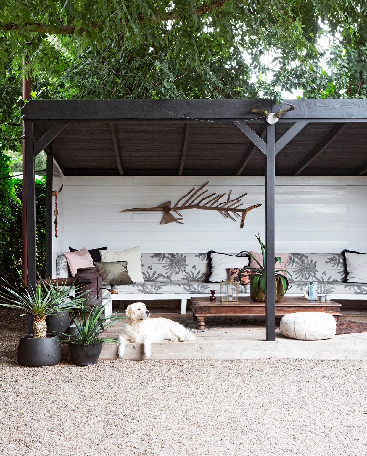 Veranda zelfgemaakt. Verf Raaf Histor en Signaalwit Histor. Bank zelfgemaakt. Kussens matrassen van Ikea bekleed met stof Kwantum. Perzisch tapijt, koperen ketels, tafel, gouden plantenbak, potkachel Marktplaats. Vloerkleed zwart met beige Goods4Home. Rubberen manden Loods 5. Stoel Ibiza Outdoor. Poef beurs vtwonen. Grote kussens H&amp;M Home. Kleine kussens Wehkamp. Hoorn Goods4Home. Ketting rommelmarkt. Object boven bank zelfgemaakt van takken, boemerang en zaag. Bruine vaas HKliving. Windlicht Sissy-Boy Homeland.Viskaraf gekocht in Griekenland. Mokken Wehkamp. Kandelaar uit ouderlijk huis meegenomen.