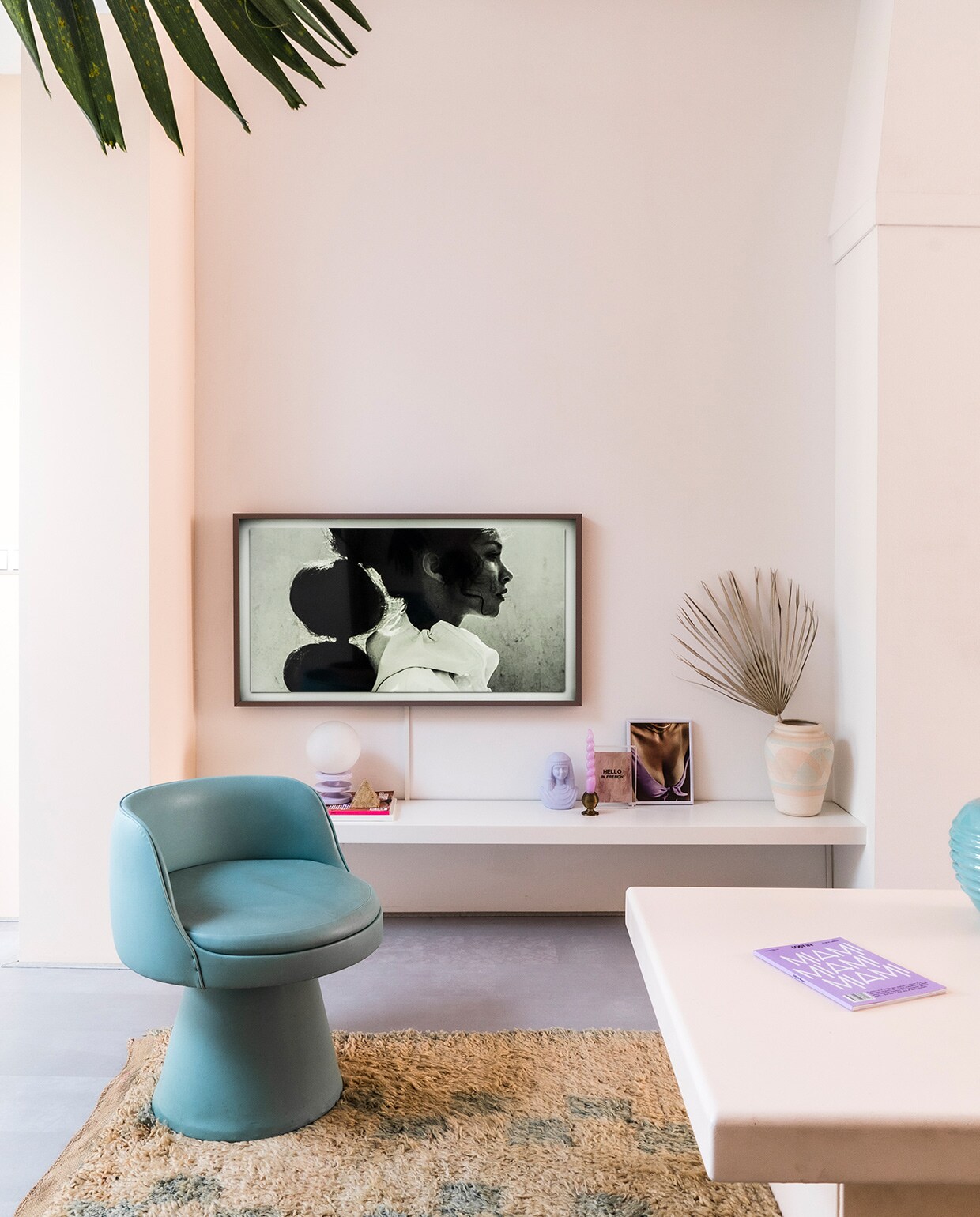 Muur, wandplank en salontafel geschilderd in kleur Ontwaak Histor. Vintage stoel en salontafel Marktplaats. Vloerkleed The Souks. Televisie The Frame van Samsung met een Pinterest-foto erop. Vintage lila bollamp Enter My Attic. Lila geverfde buste en kandelaar kringloop. Roze kaars Hay. Print Hello in French Hôtel Magique via . Ingelijst knipsel uit tijdschrift. Vaas meegenomen uit Palm Springs. Groene bolvaas rommelmarkt.