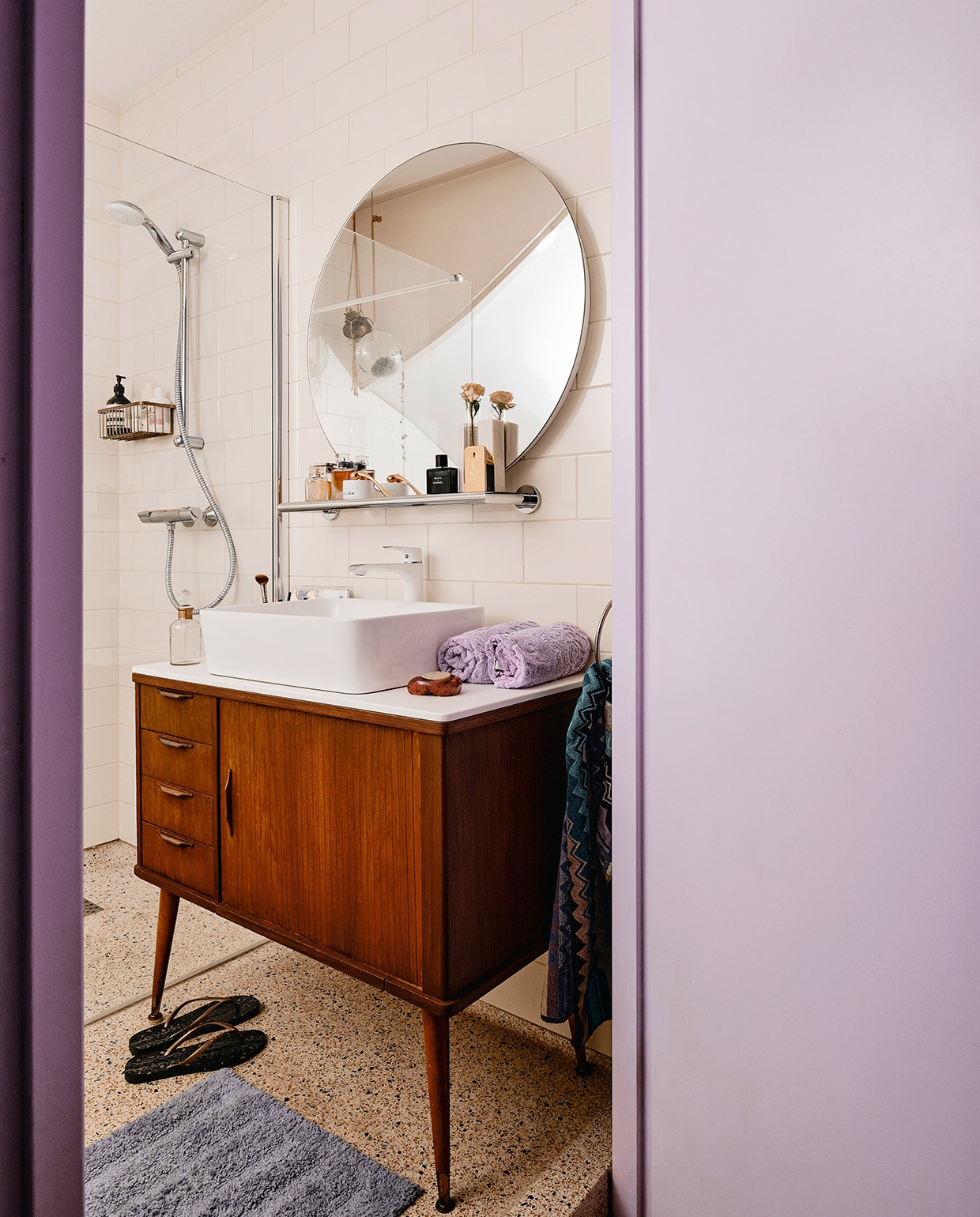 Tegels en douchekraan onbekend. Wastafelmeubel, wasbak en kraan Sixty Fruits. Spiegel Sanitairwinkel. Paarse handdoek Zara Home. Handdoek met dessin Missoni. Badmat Ikea. Rekje House Doctor.